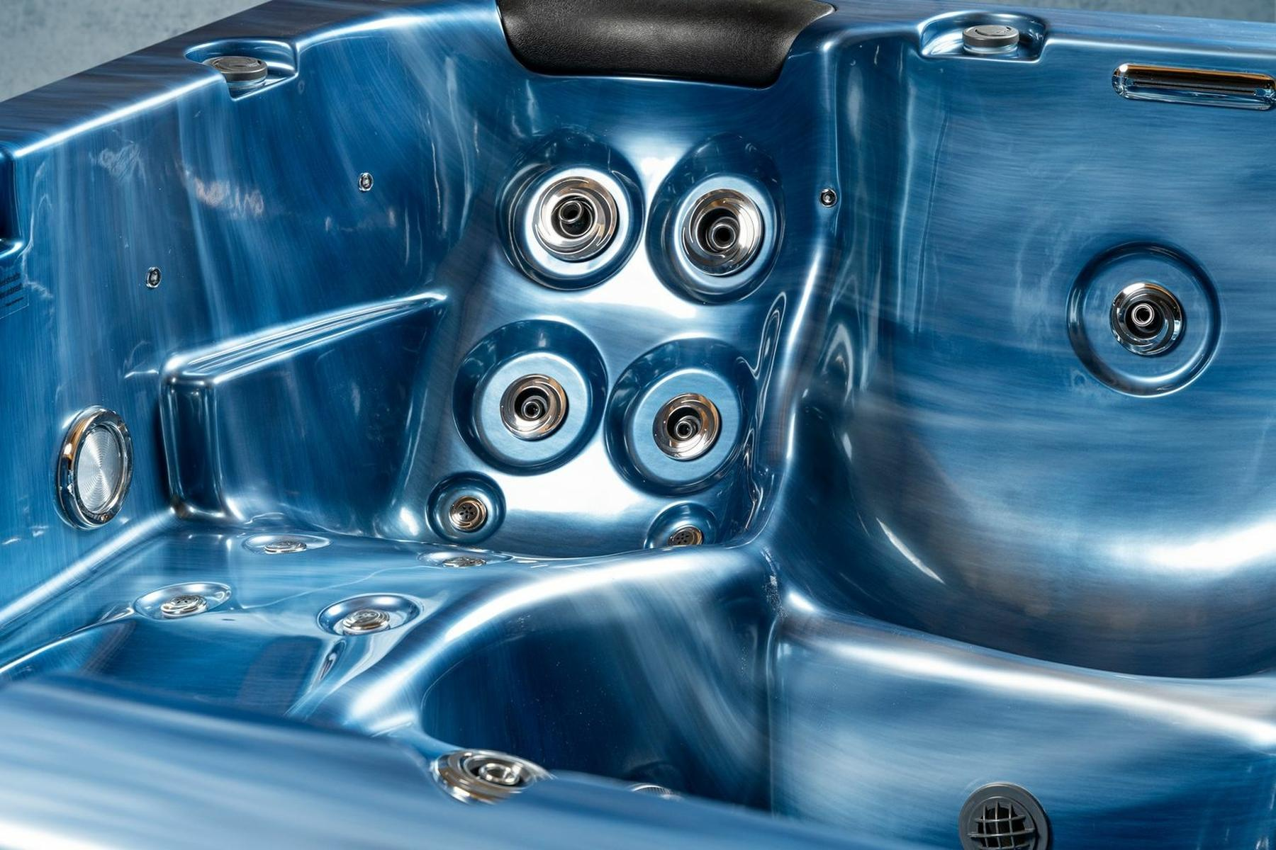 Nahaufnahme des Inneren eines blauen Whirlpools mit Düsen und glänzender Oberfläche.