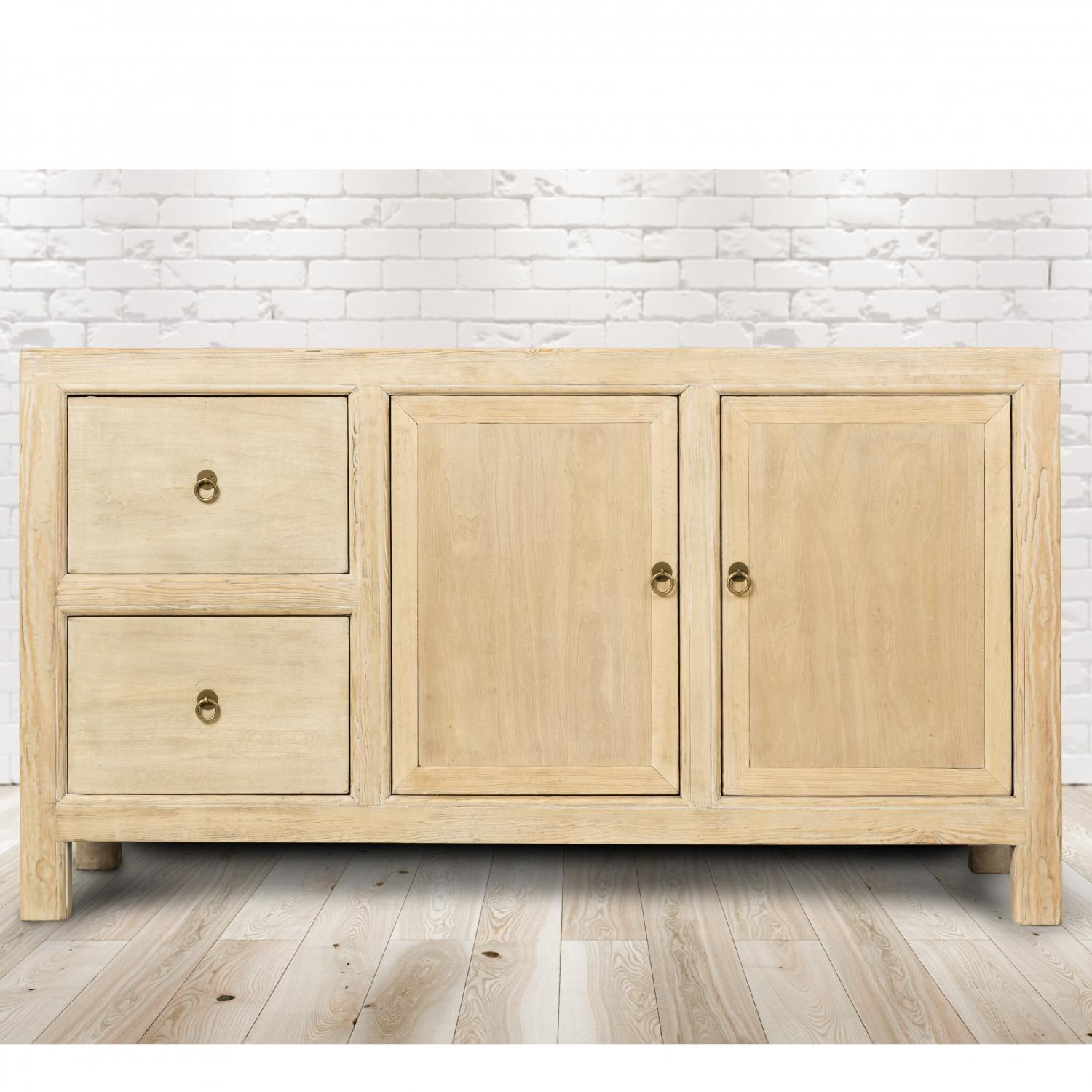 Schrank aus hellem Holz mit zwei Schubladen und zwei Türen. Messinggriffe. Weißer Backsteinwand-Hintergrund.