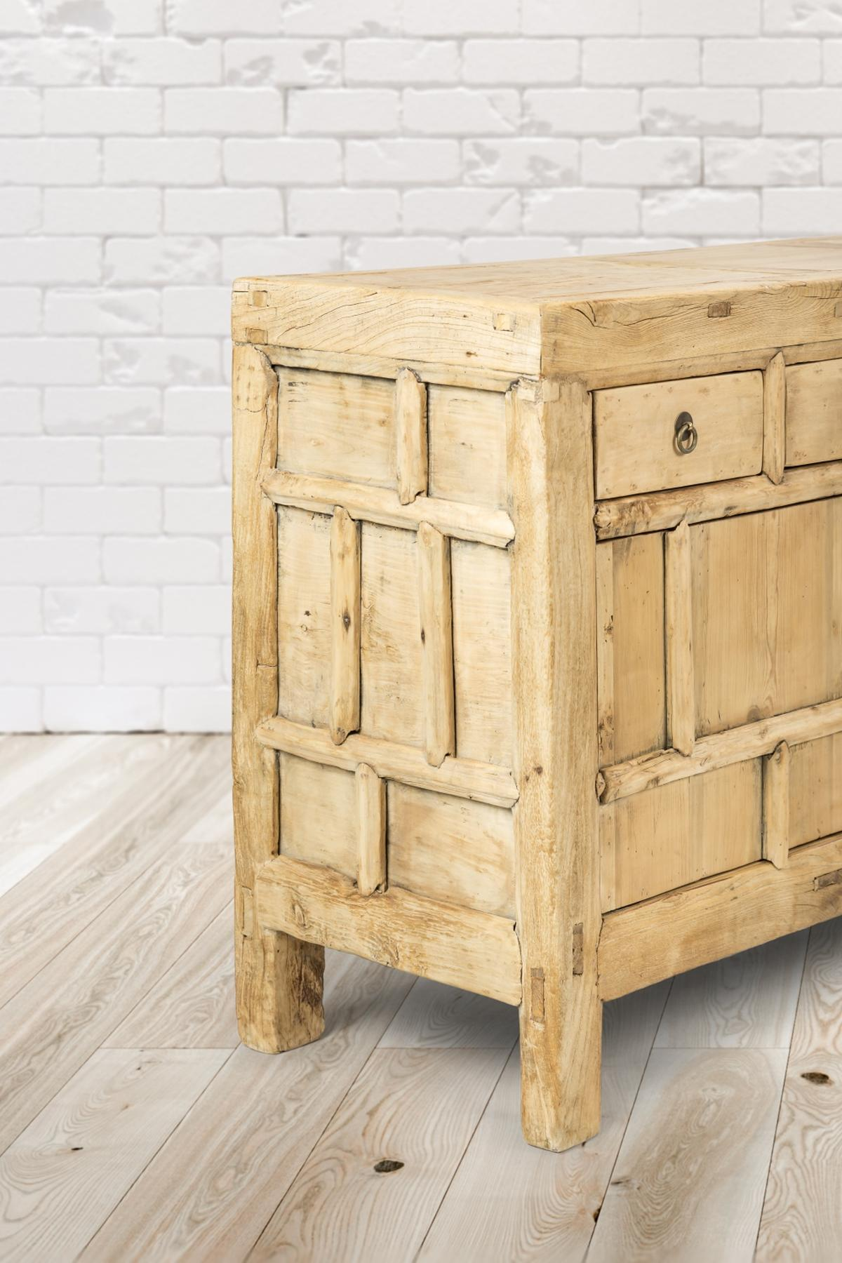 Holztruhe mit Schublade. Hellfarbenes Holz mit Backsteinmauer im Hintergrund.