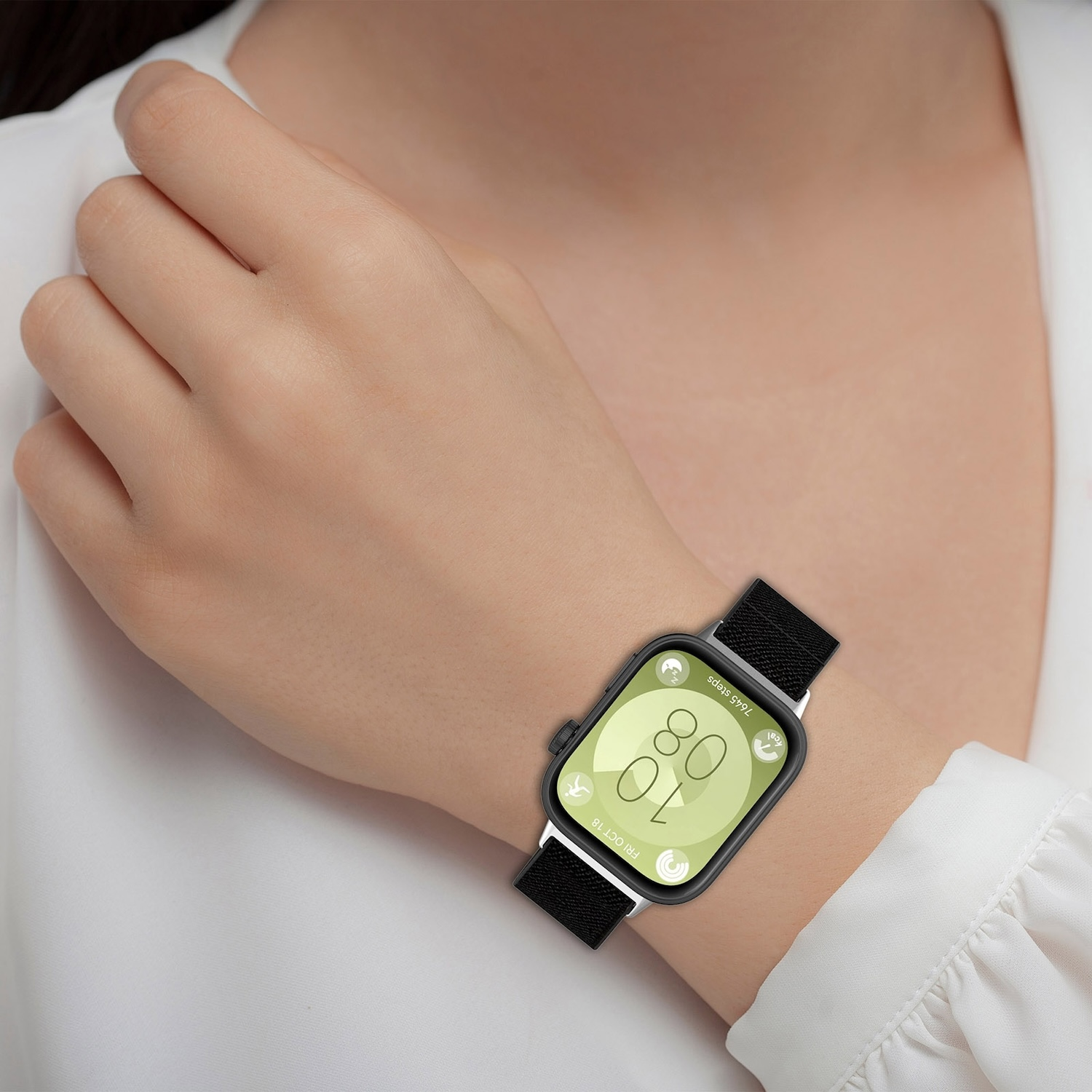 Das Handgelenk einer Frau mit einer Smartwatch, die Zeit und Datum anzeigt.