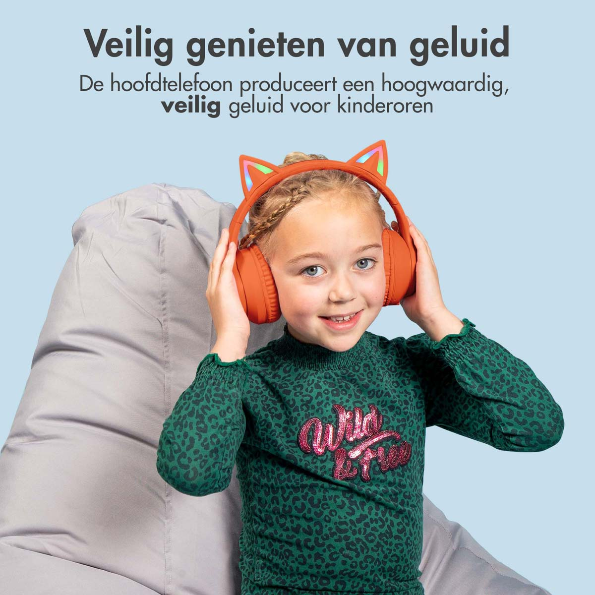 Meisje met een oranje koptelefoon met kattenoren. Ze lacht. Grijze zitzak.