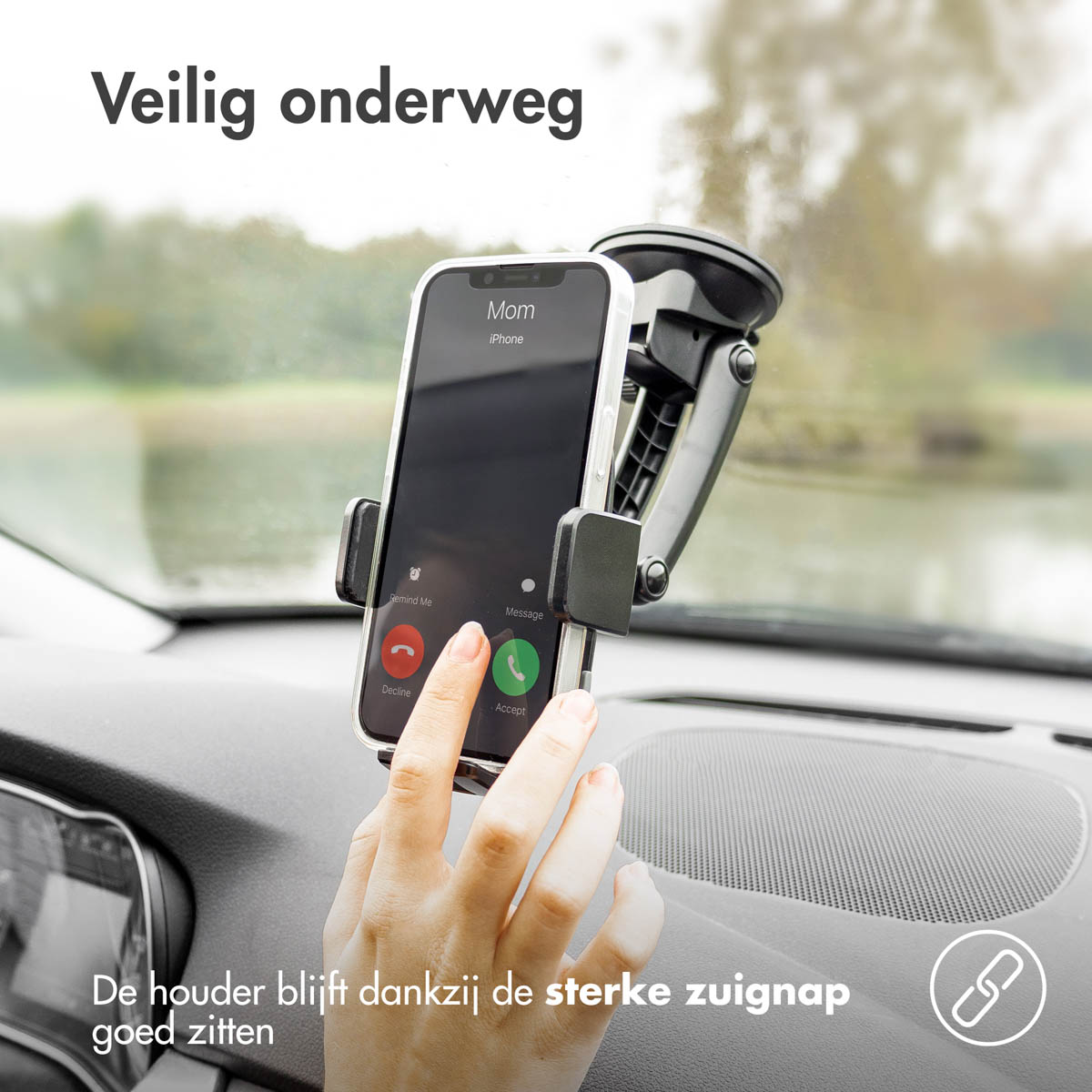 A car dashboard showing a phone in a car mount. Phone displays an incoming call. Hands are visible.