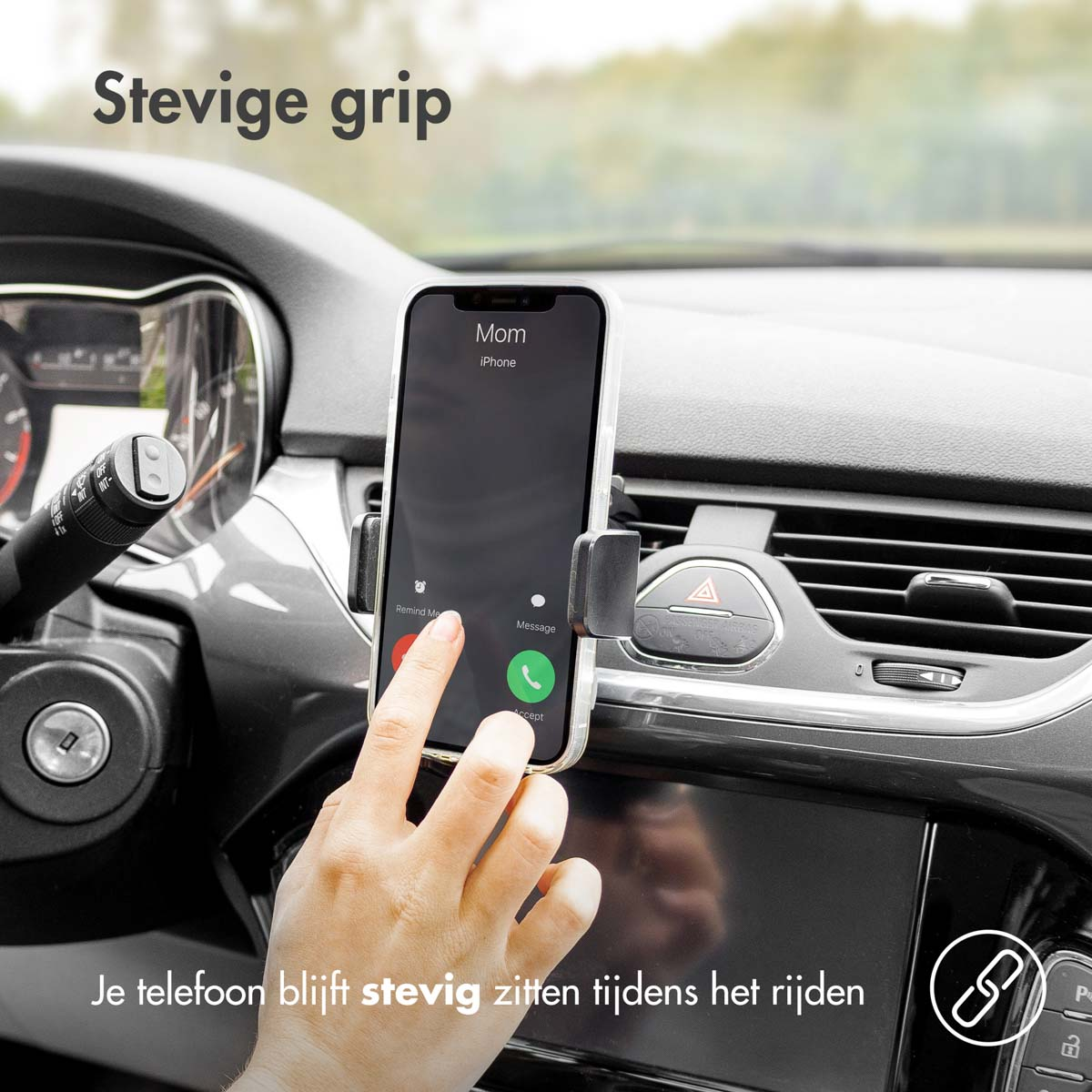 A phone is in a car mount. A hand is touching the screen. The phone displays a call from Mom.