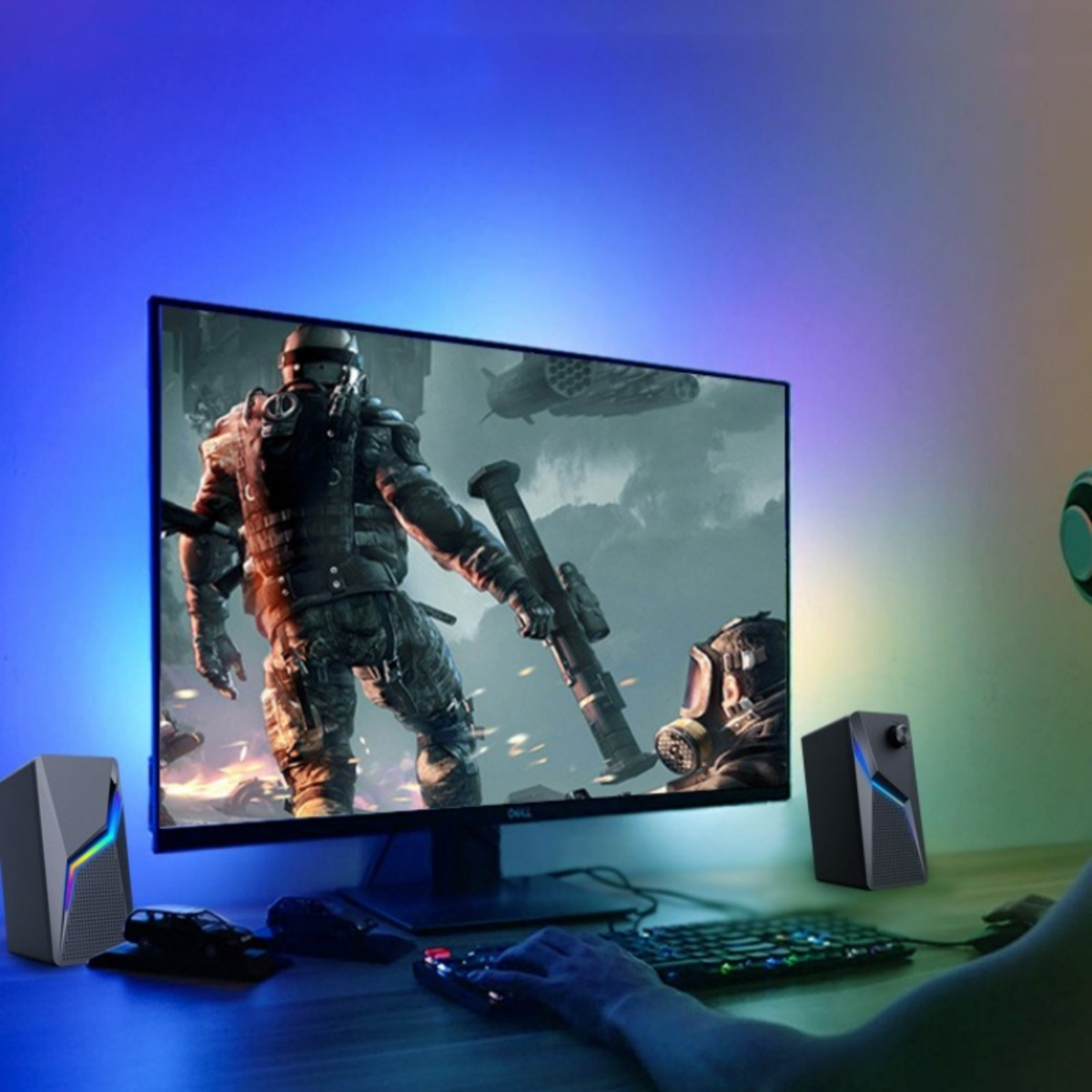 Gaming-Setup mit großem Monitor, spielender Person und zwei Lautsprechern an den Seiten.