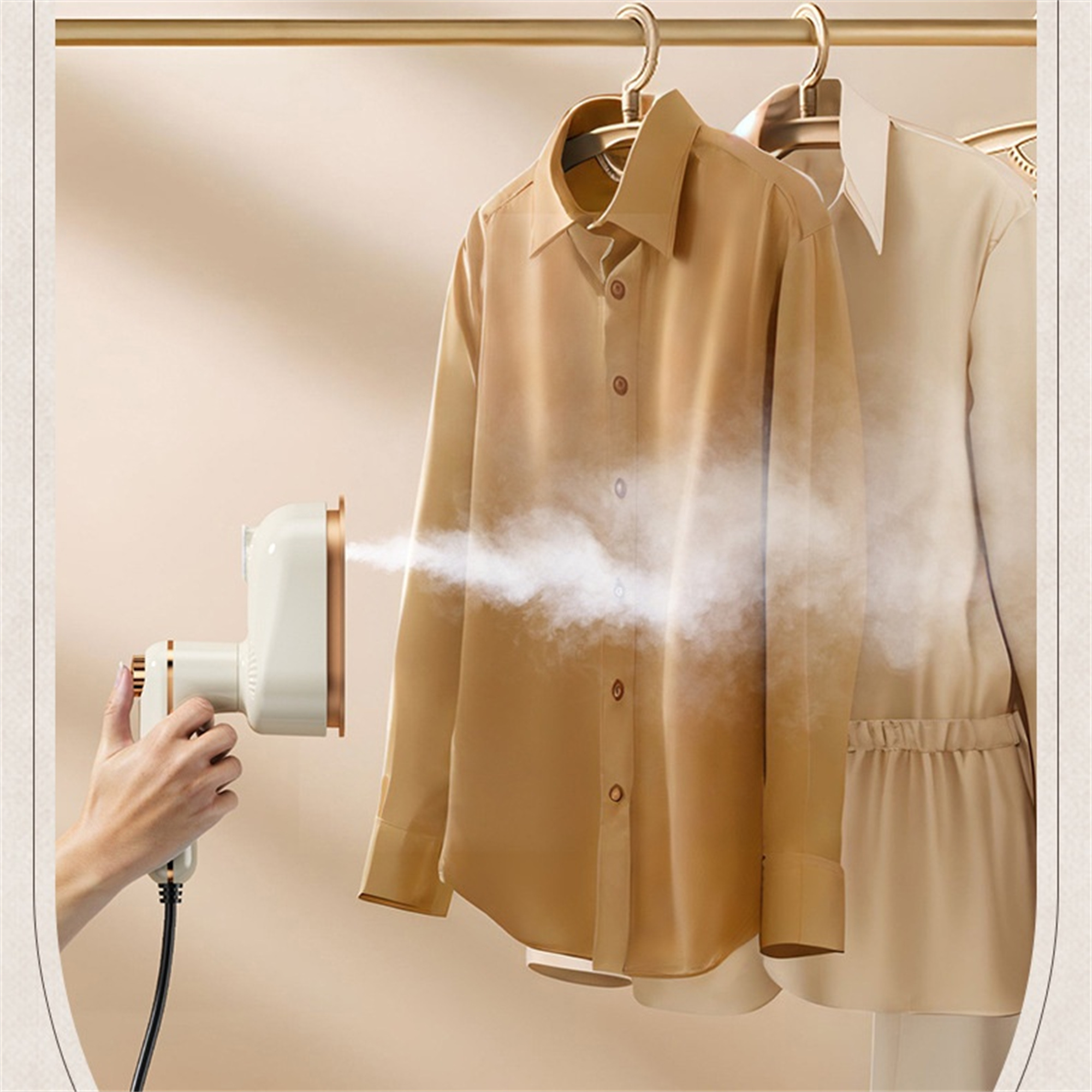 Eine Hand hält einen Steamer und dämpft ein Hemd. Ein weiteres Hemd hängt auf dem Gestell. Ein goldenes Gestell wird gezeigt.