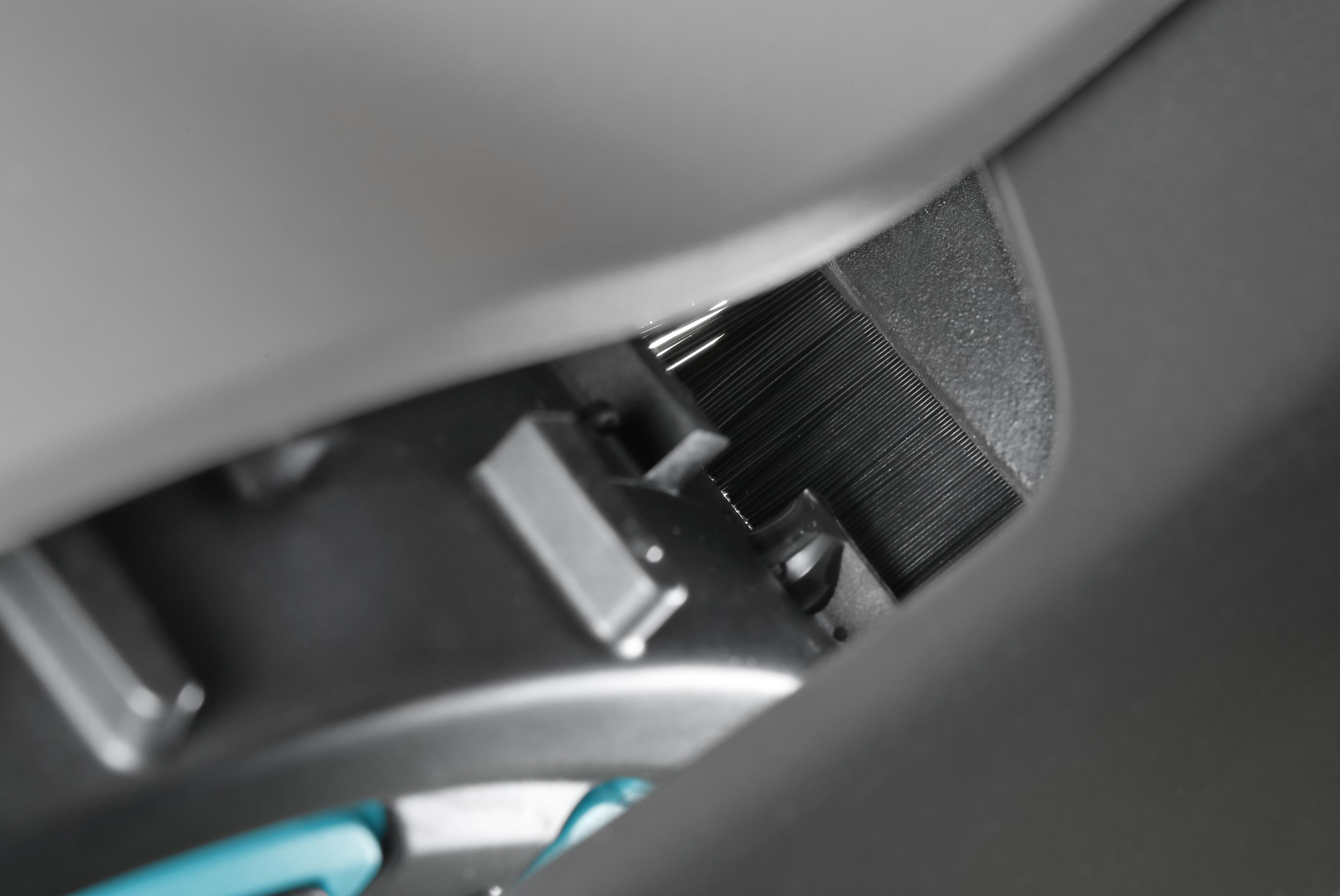 Nahaufnahme des Inneren eines Autos, die eine dunkle Kunststoffplatte mit kleinen Details zeigt.