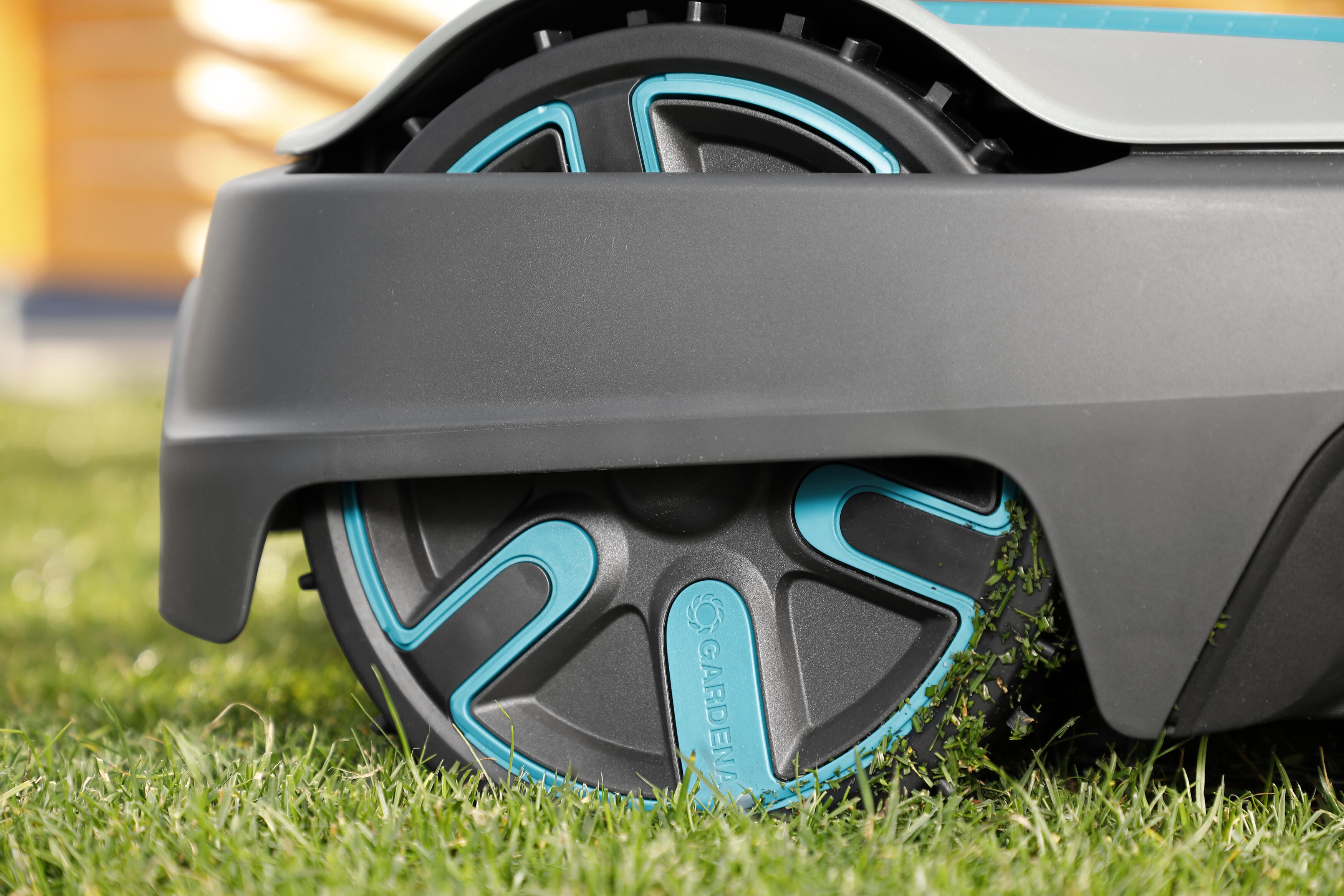 Nahaufnahme eines Roboter-Rasenmäherrads auf Gras, mit einem schwarz-türkisen Design.
