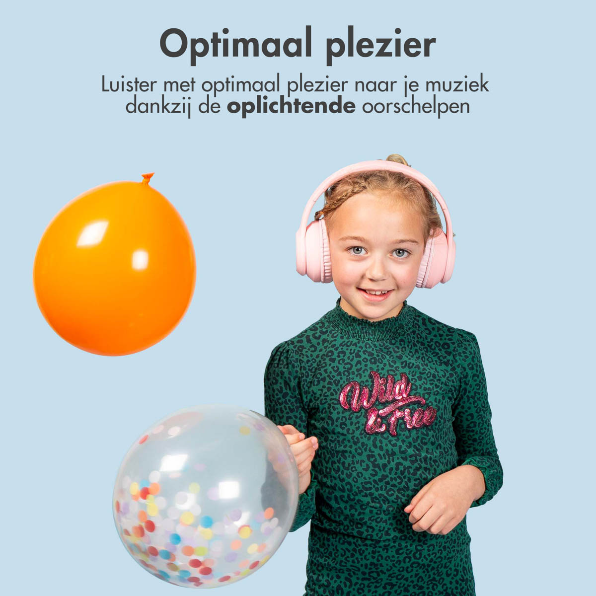 A child wearing pink headphones and smiling. They hold a orange balloon and a confetti-filled balloon.