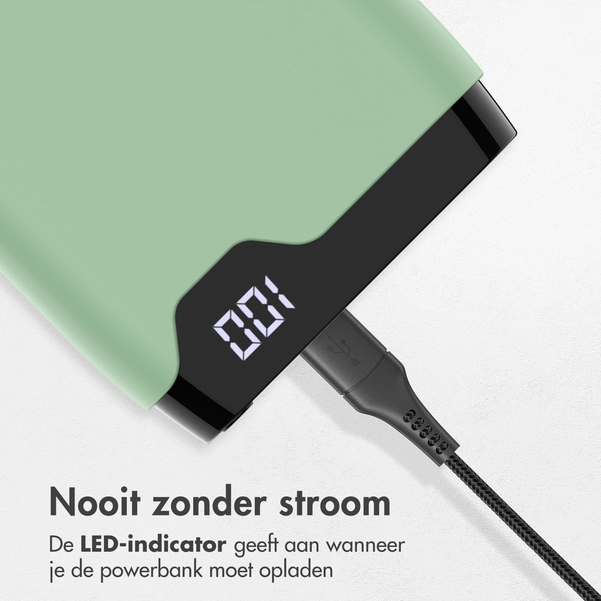Power bank verte avec un affichage numérique indiquant 100%. Un câble noir est branché.