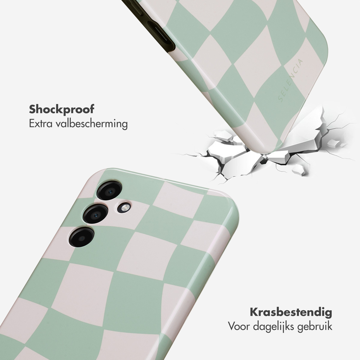 Telefoon valt, gebarsten grond, telefoonhoesje met groen en wit ruitpatroon. Tekst: Schokbestendig, krasbestendig.