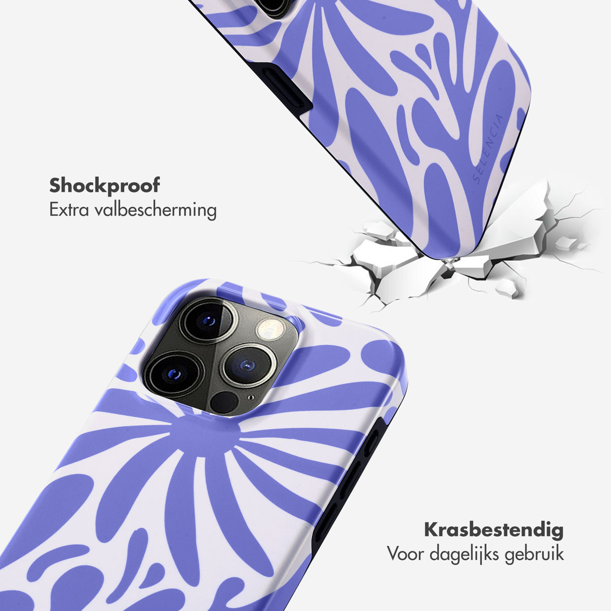Téléphone dans une coque avec un motif floral bleu et blanc. La coque est sur une surface blanche, à côté d'une surface fissurée.