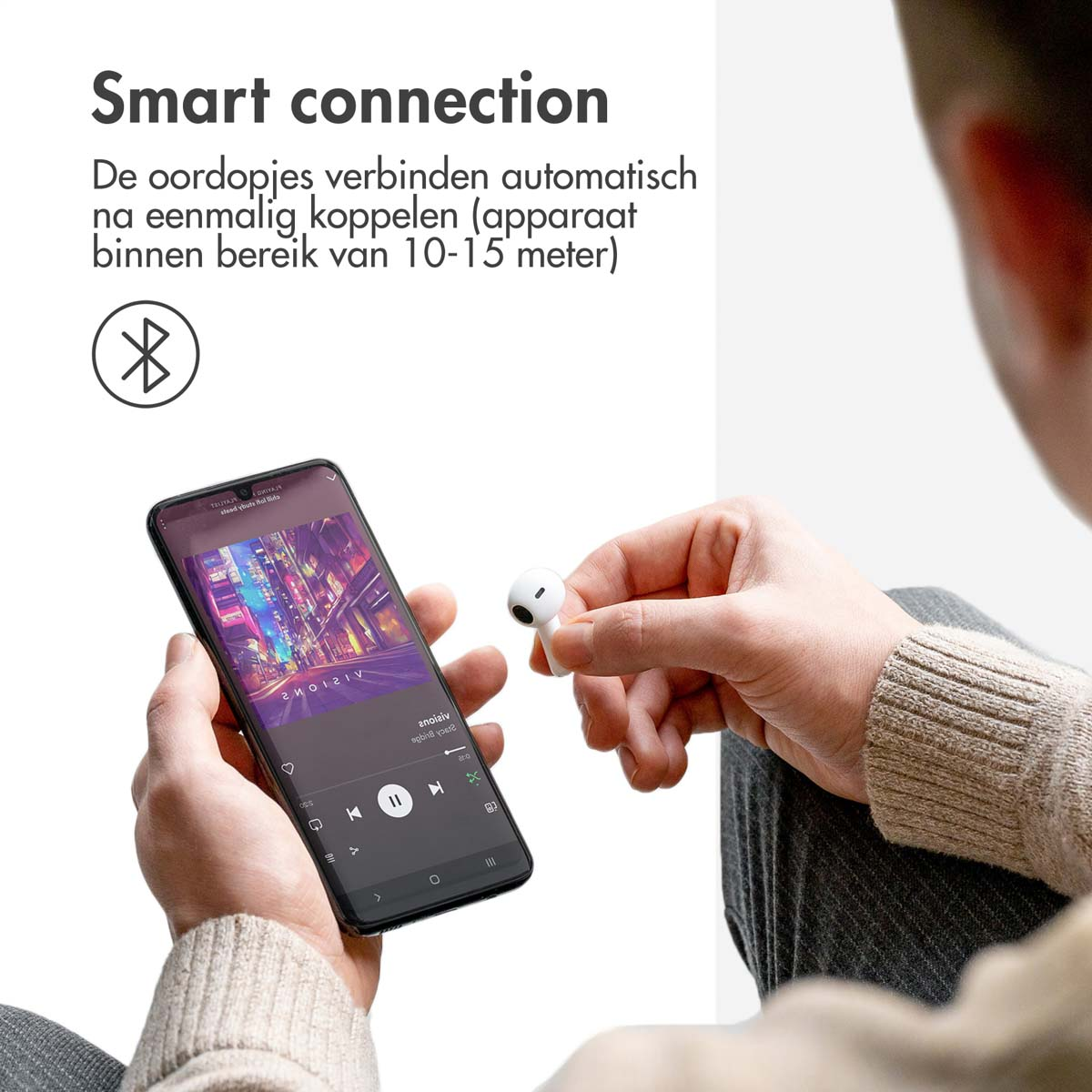 Person holding white earbuds next to a smartphone showing a music app.