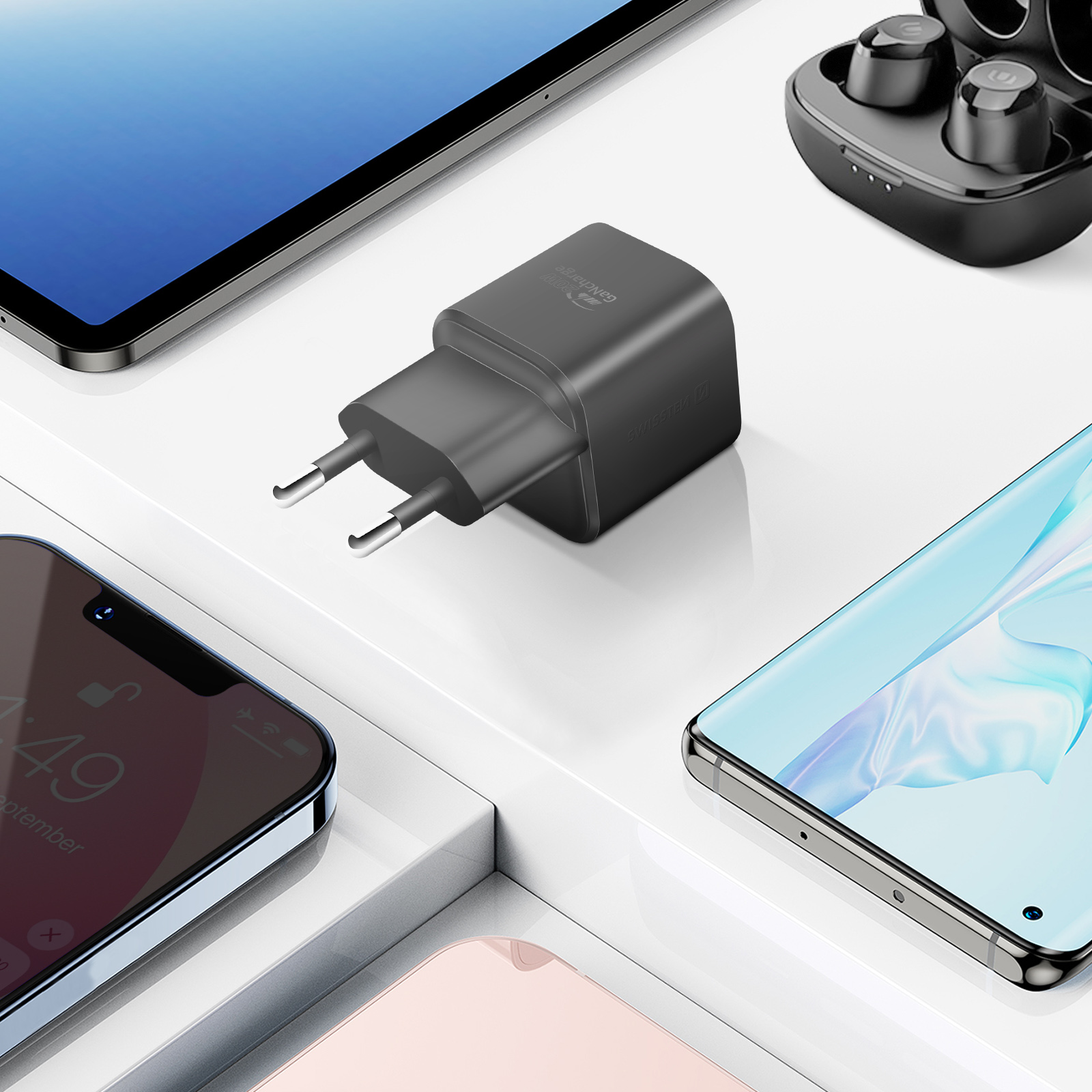 Ein Ladegerät, Telefon, Tablet und Ohrhörer auf weißer Oberfläche.