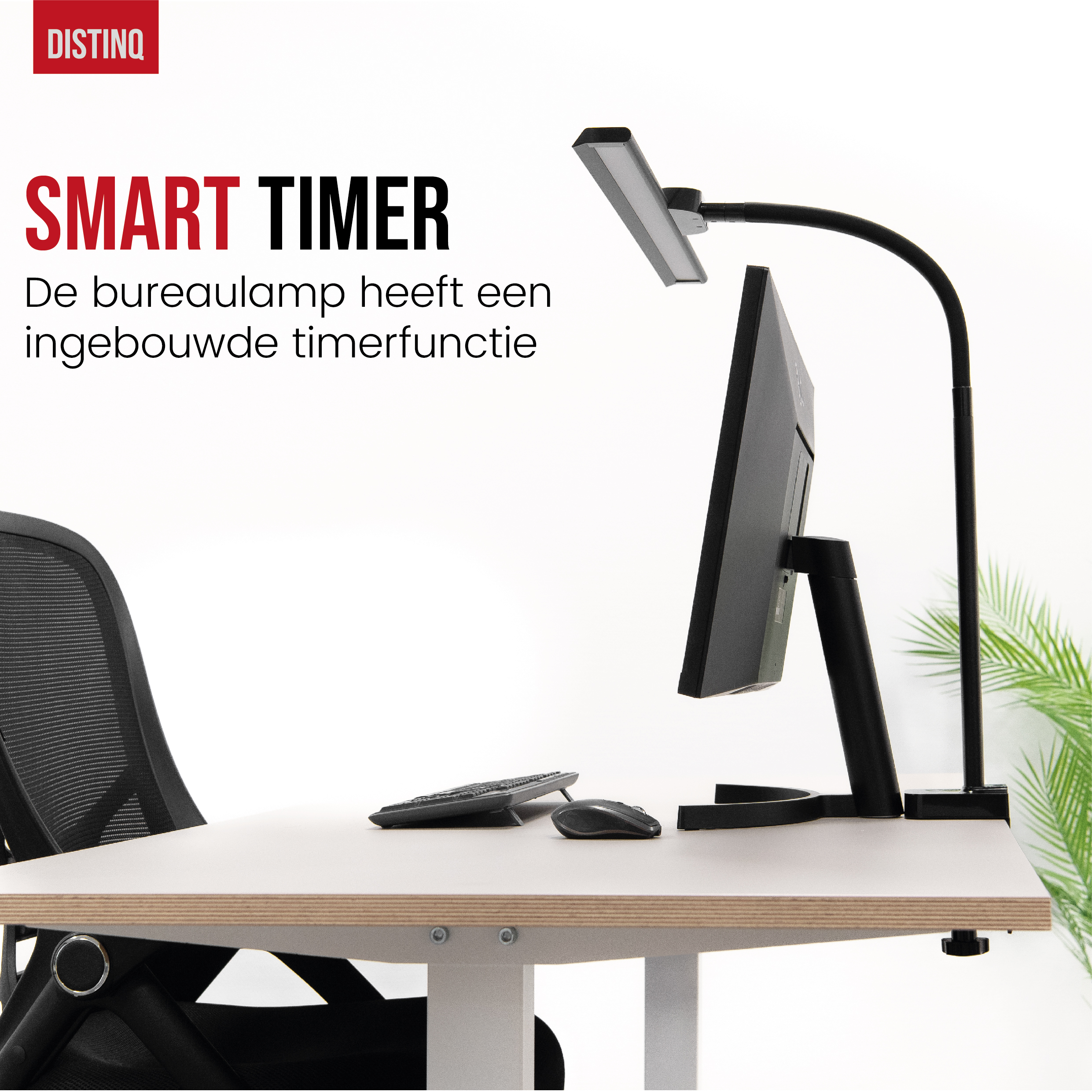 Een zwarte bureaulamp met een monitor, toetsenbord en muis op een witte tafel. Een zwarte stoel op de achtergrond.