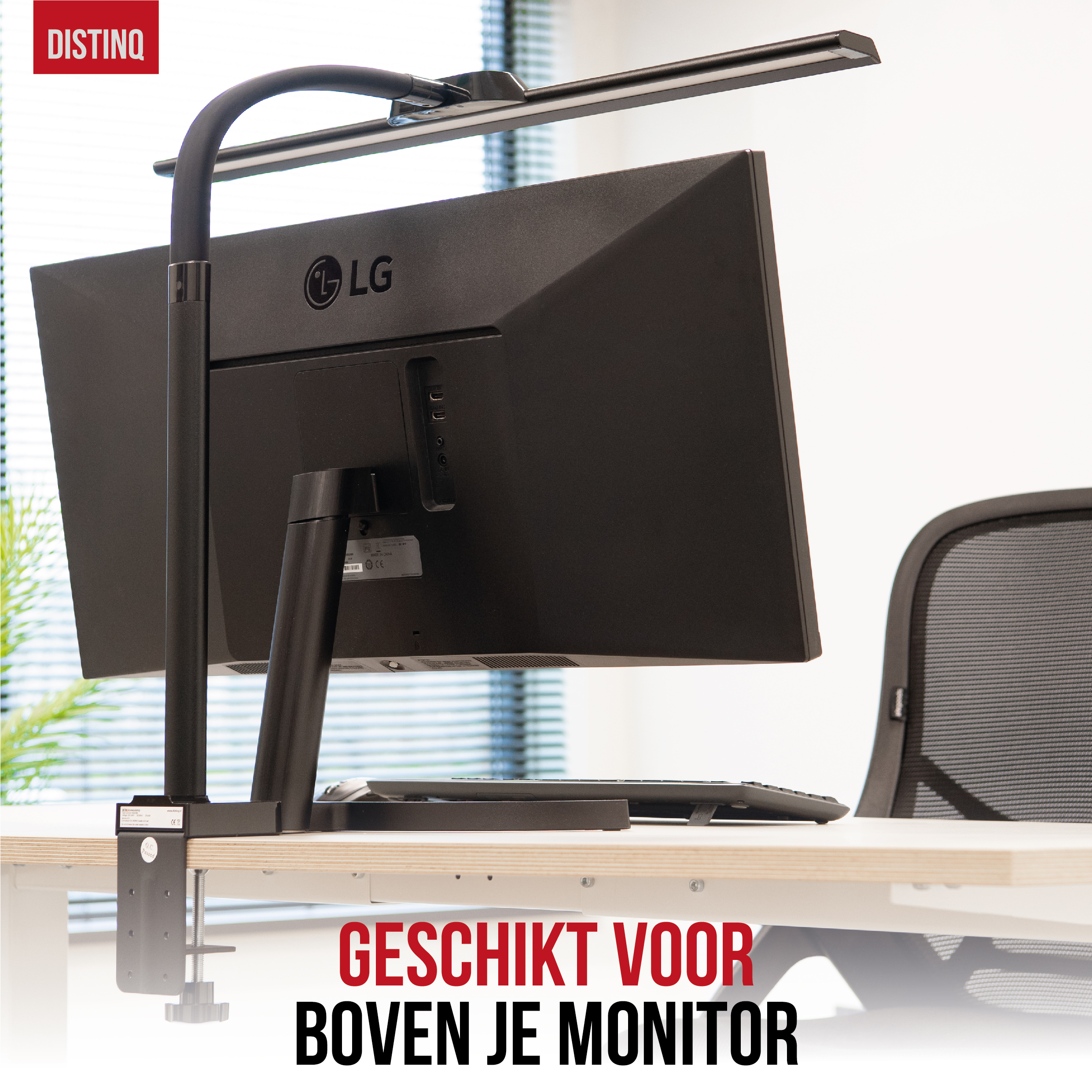 Zwarte monitor, zwarte bureaulamp, witte bureau en zwarte bureaustoel op de achtergrond.