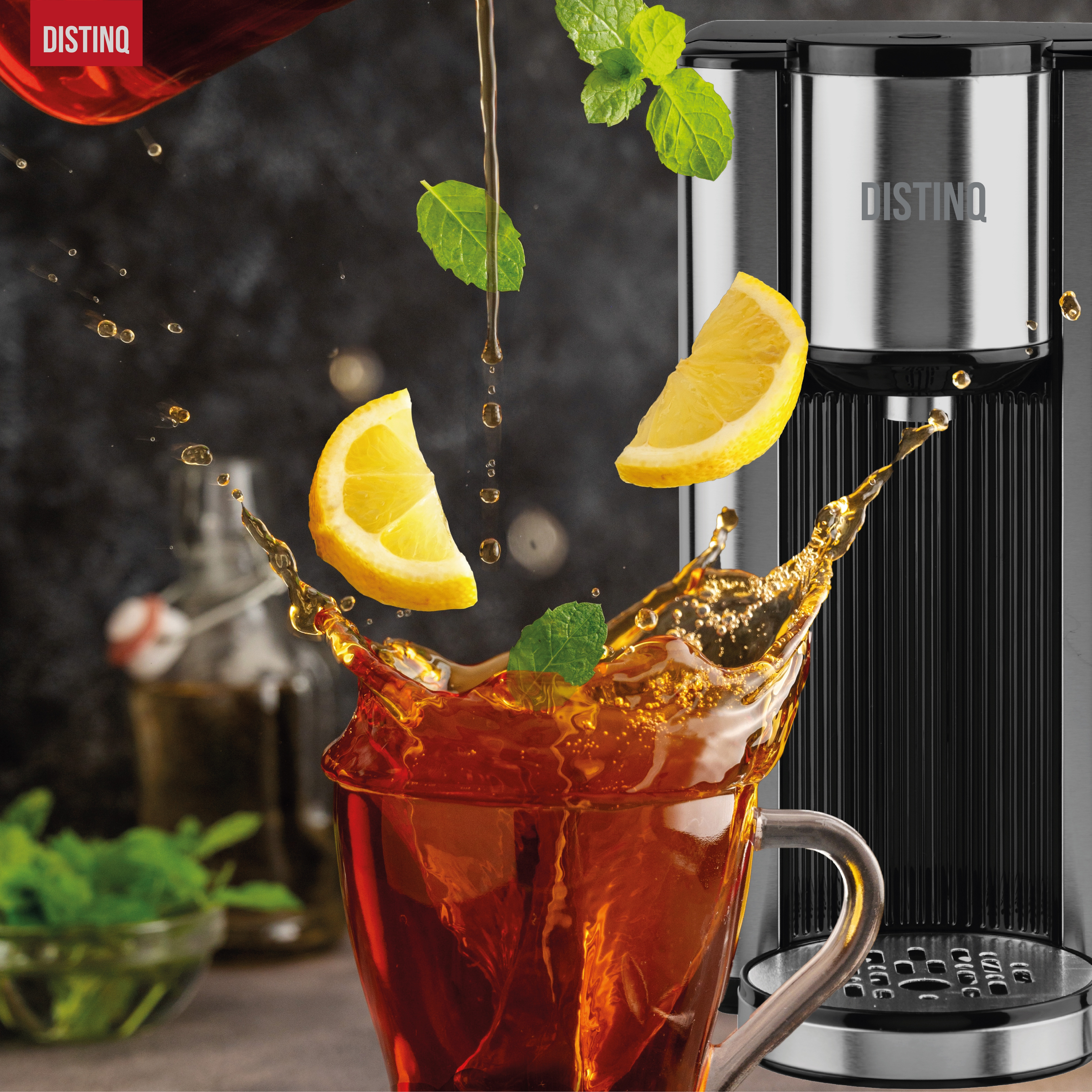 Tea pouring into a clear glass with lemon slices and mint leaves. A Disting tea maker is in the background.