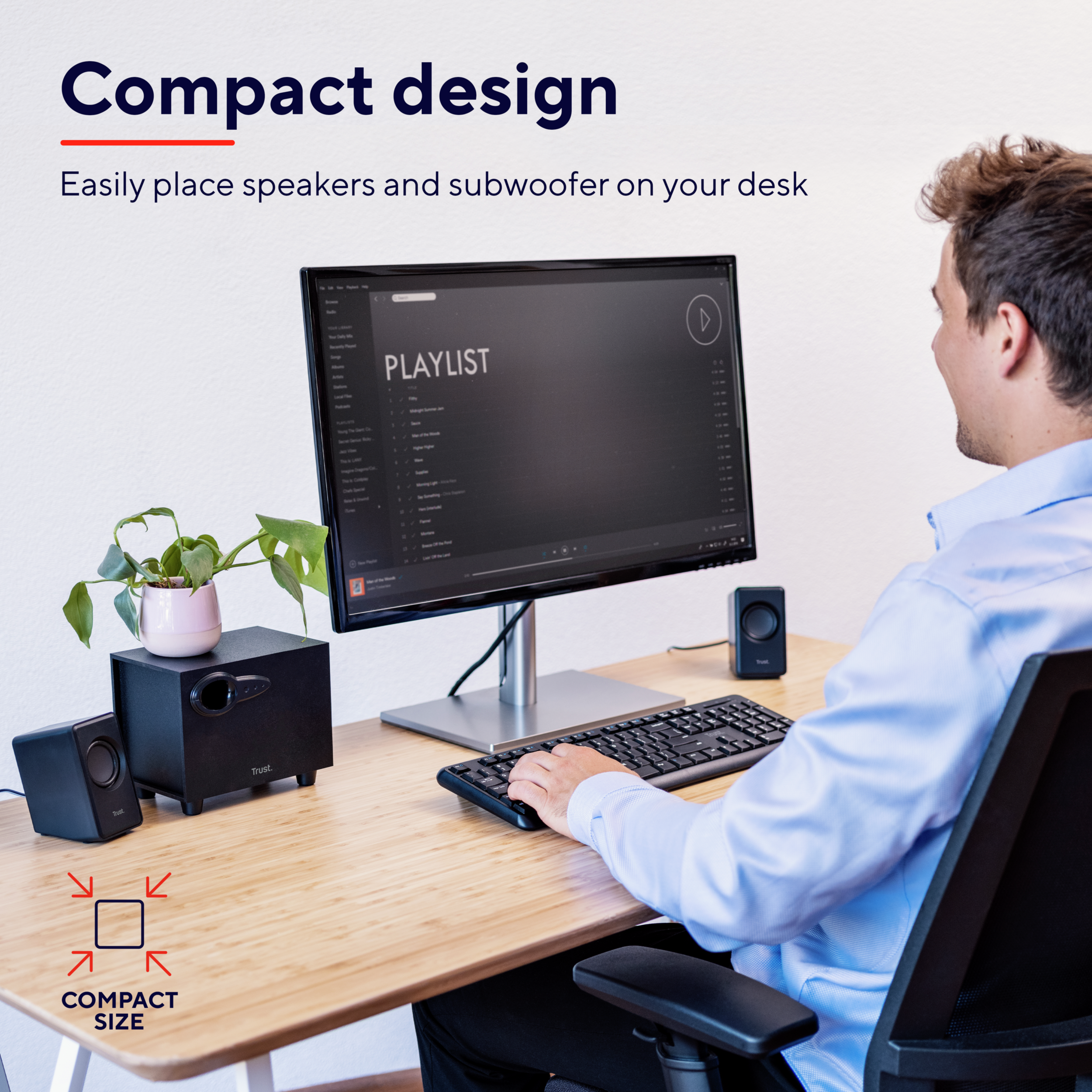 Mężczyzna siedzi przed biurkiem z głośnikami i subwooferem.