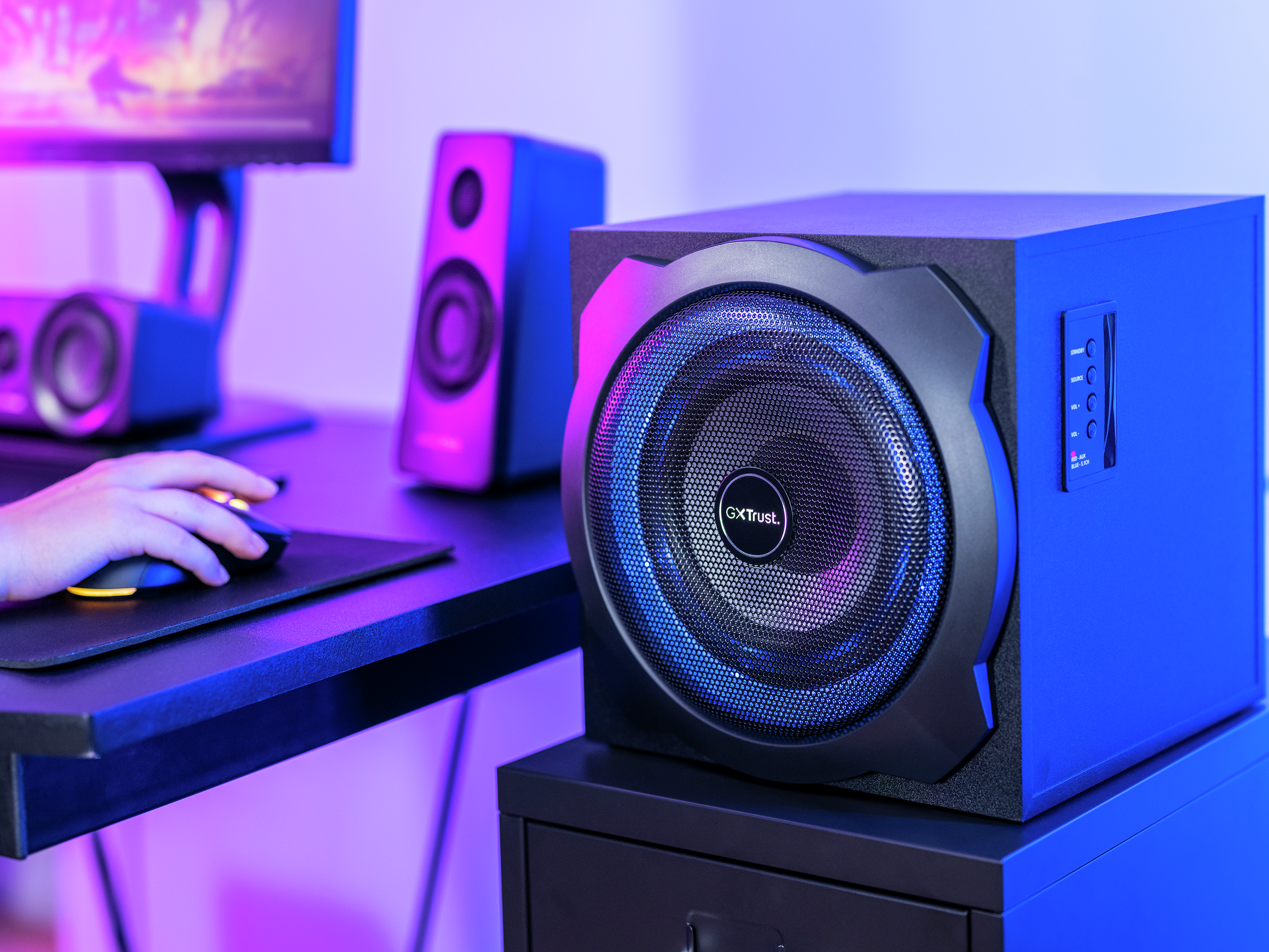Ein schwarz-blaues Lautsprechersystem mit einem Computer-Setup auf dem Schreibtisch.