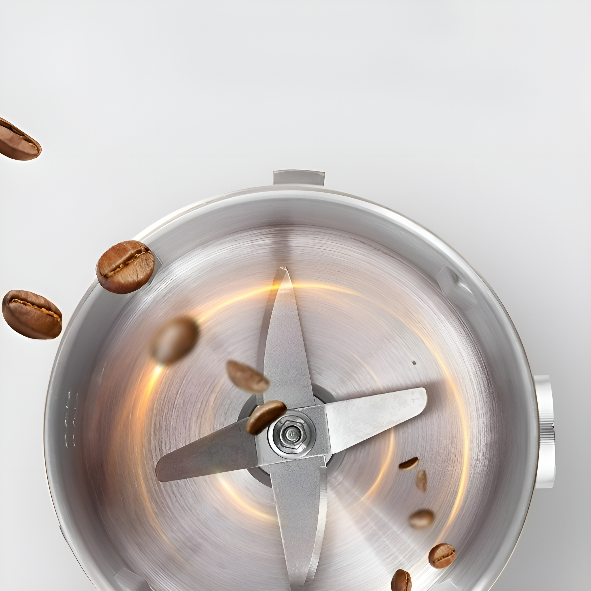 Nahaufnahme einer Kaffeemühle mit Kaffeebohnen, die auf eine Klinge fallen. Die Mühle ist aus Edelstahl gefertigt.