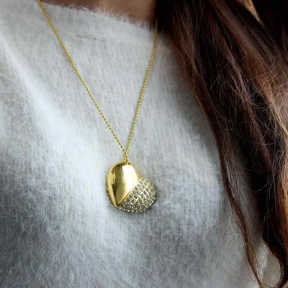 Eine goldene Herz-Halskette auf einem weißen Pullover, mit einem funkelnden Abschnitt.