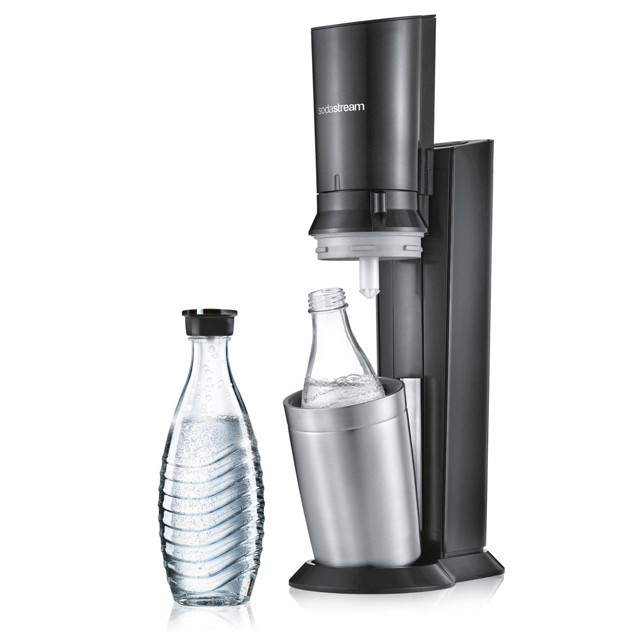 A black SodaStream machine with a glass bottle of water to the left and a bottle inside the machine.