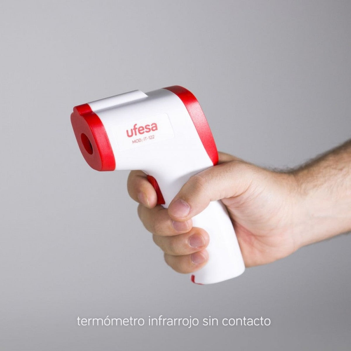 Una persona sosteniendo un termómetro infrarrojo sin contacto Ufesa blanco y rojo.