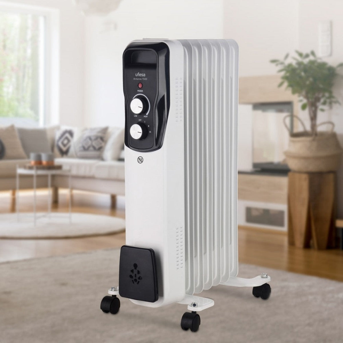 Biały grzejnik olejowy na kółkach, z czarnym panelem sterowania i czarną podstawą. W pokoju.