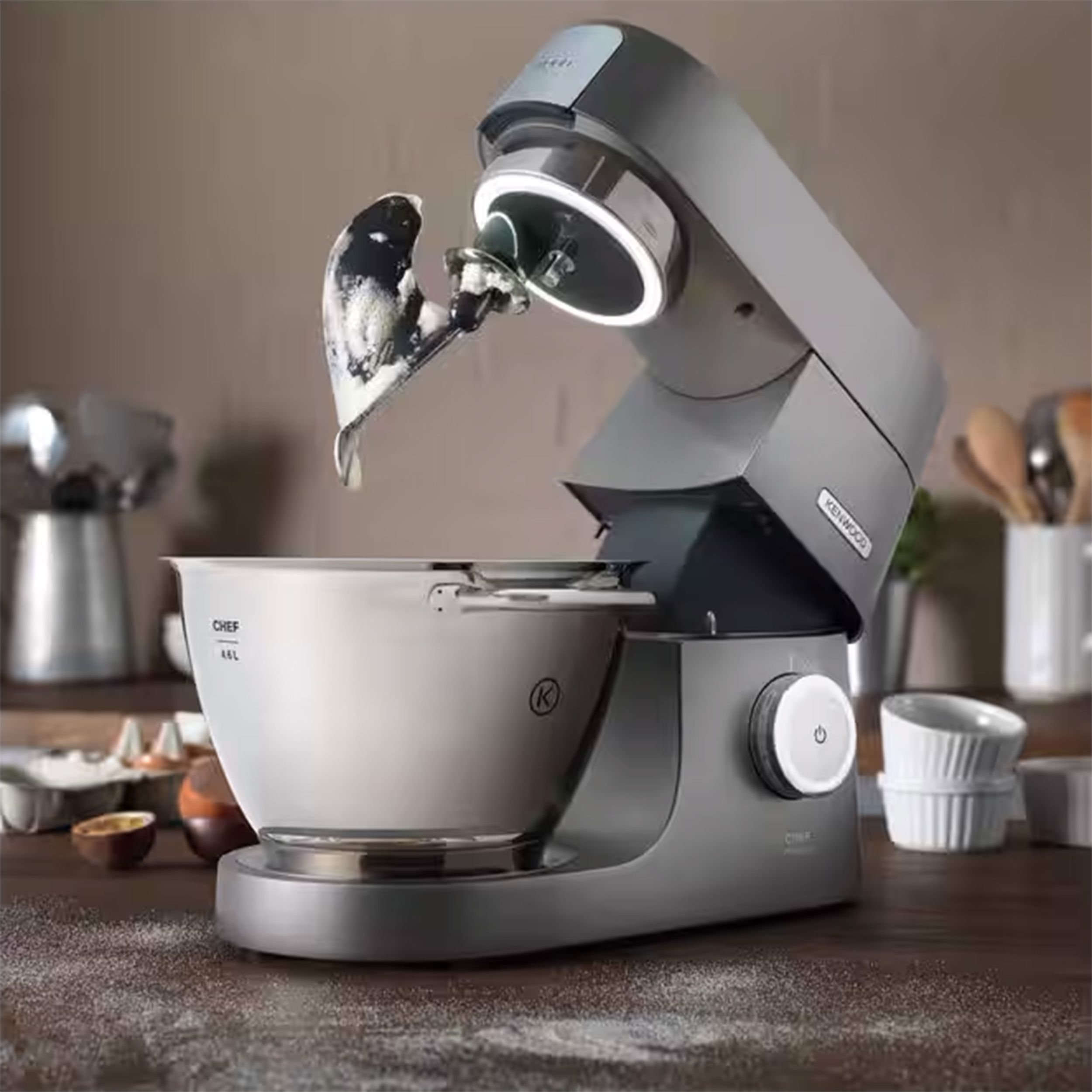 Un mixer da cucina argento e grigio sta mescolando gli ingredienti in una ciotola grande.