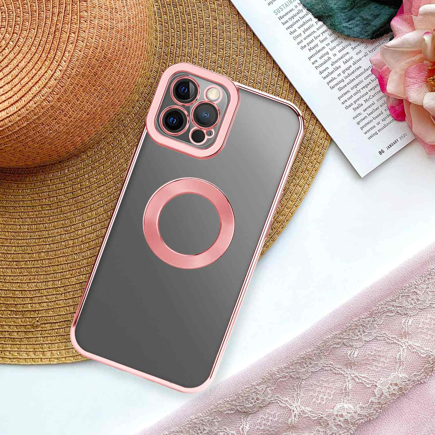 Telefon in einem roségoldenen Gehäuse mit einer Zeitschrift und einem Hut im Hintergrund.
