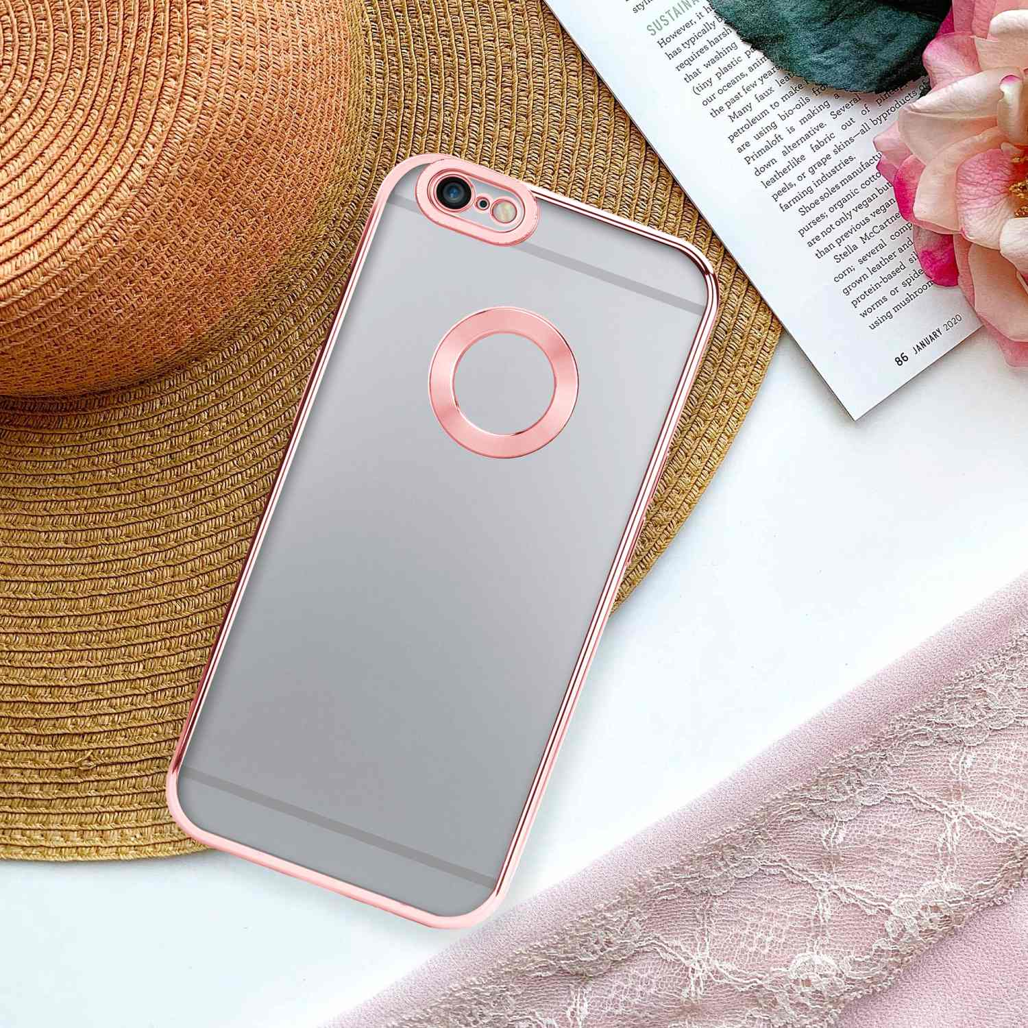 Transparente Handyhülle mit rosa Einfassung auf einem Telefon, vor dem Hintergrund eines Magazins und Blumen.