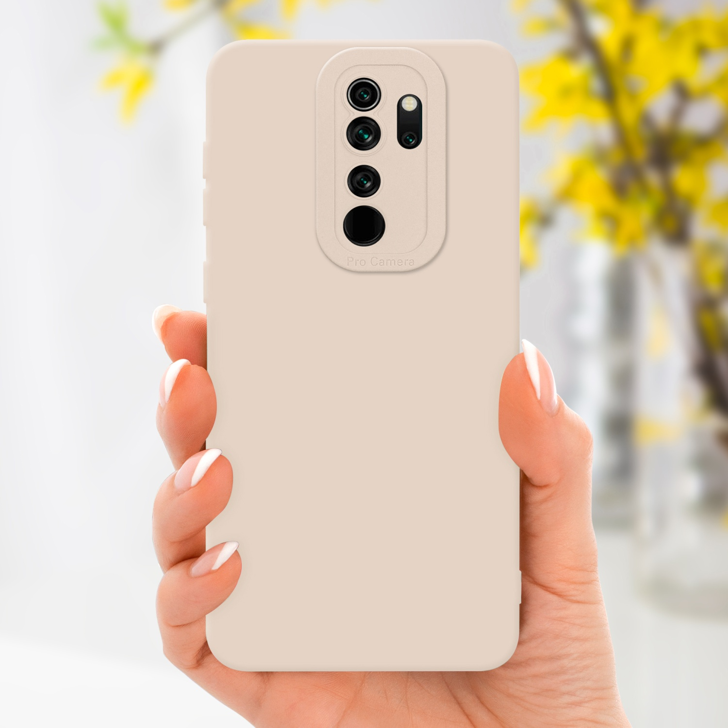 La mano di una persona che tiene una custodia beige con un rialzo per la fotocamera. Sfondo sfocato.