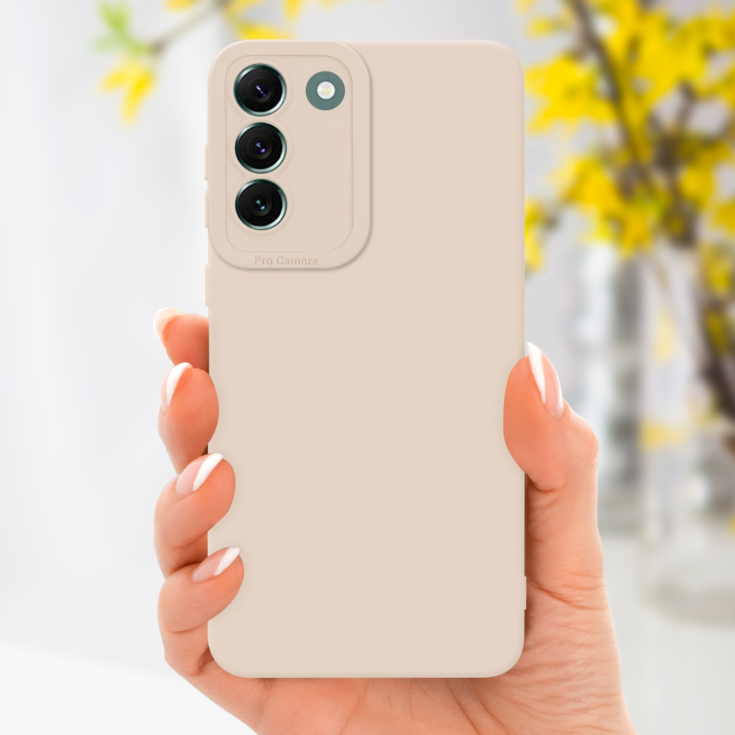Mano che tiene una custodia beige per telefono con un modulo fotocamera. Sfondo: fiori gialli.