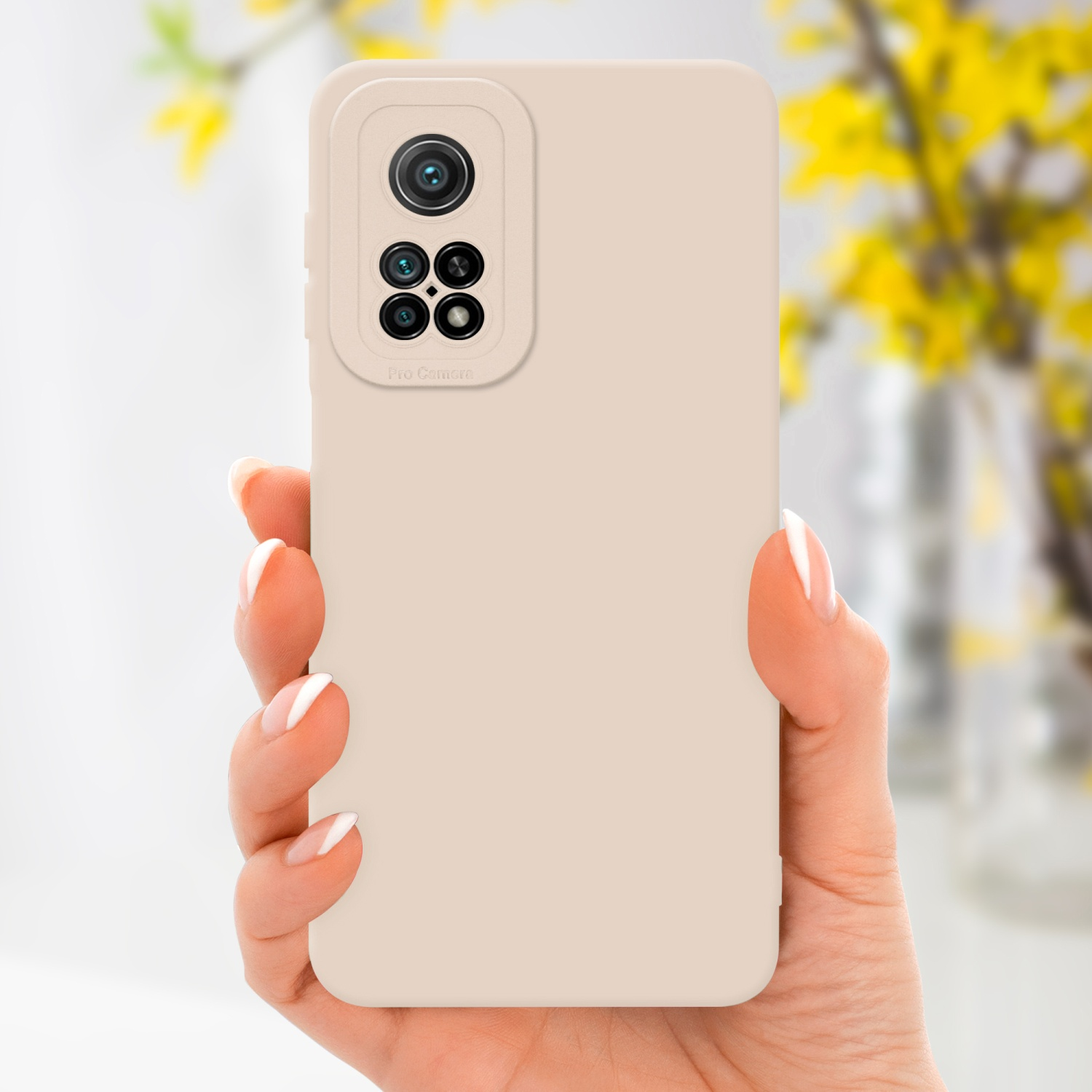 Una mano che tiene un telefono beige con un rialzo della fotocamera e una custodia beige, con uno sfondo giallo sfocato.