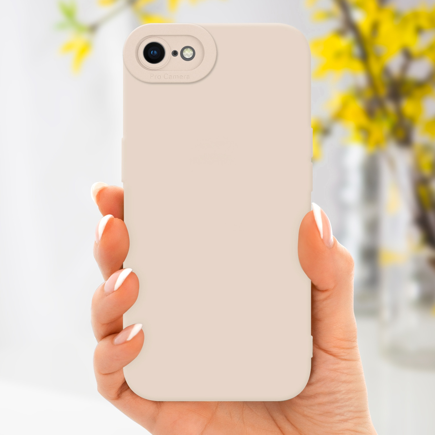 Una mano tiene una custodia beige per telefono con una fotocamera. Fiori gialli sullo sfondo sfocato.