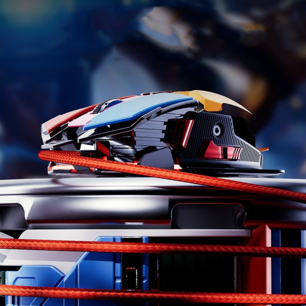 Gaming-Maus auf Metalloberfläche, rotes Kabel. Die Maus hat mehrere Farben und Designelemente.
