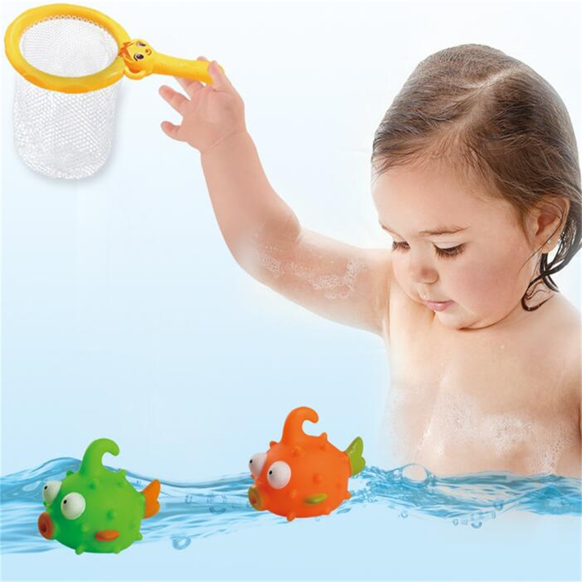 Ein Baby in einer Wanne greift nach einem gelben Netz mit einem grünen und orangen Fisch.