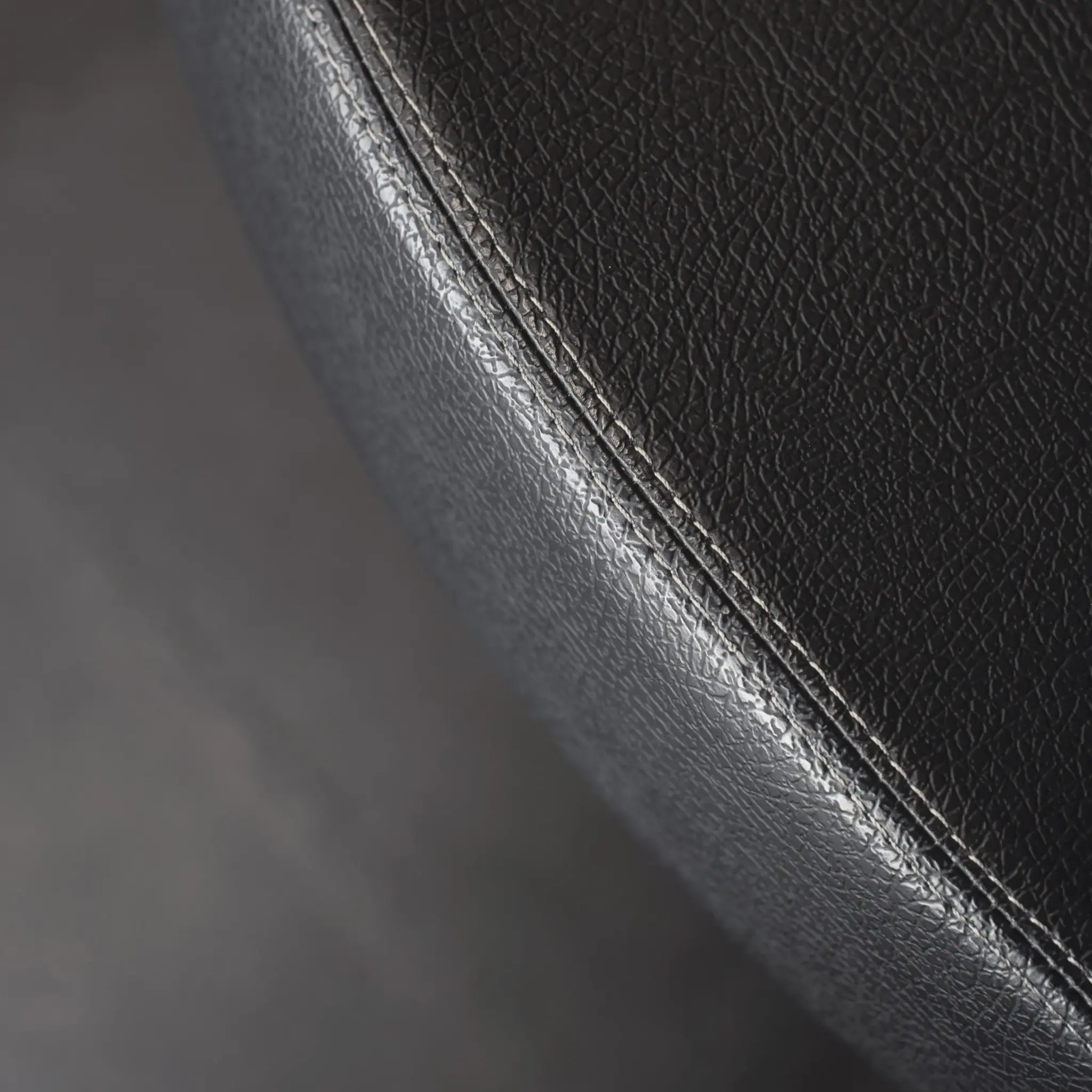 Close-up of black leather surface with a white stitching detail.