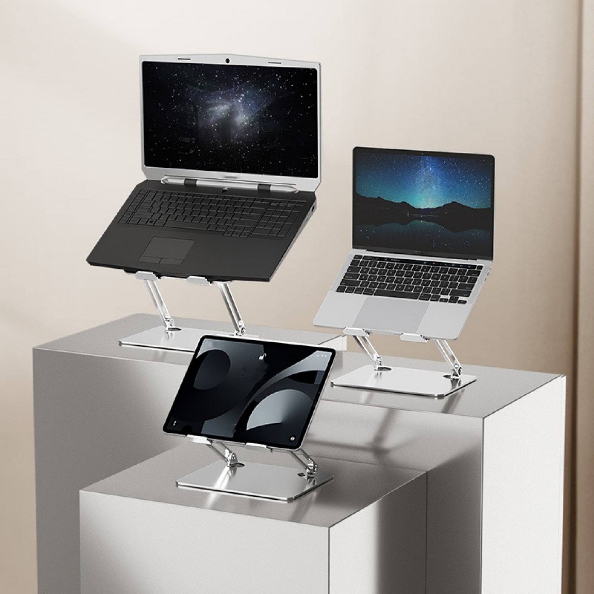 Drei Laptops und ein Tablet auf silbernen Ständern, angeordnet auf einer silbernen Oberfläche.