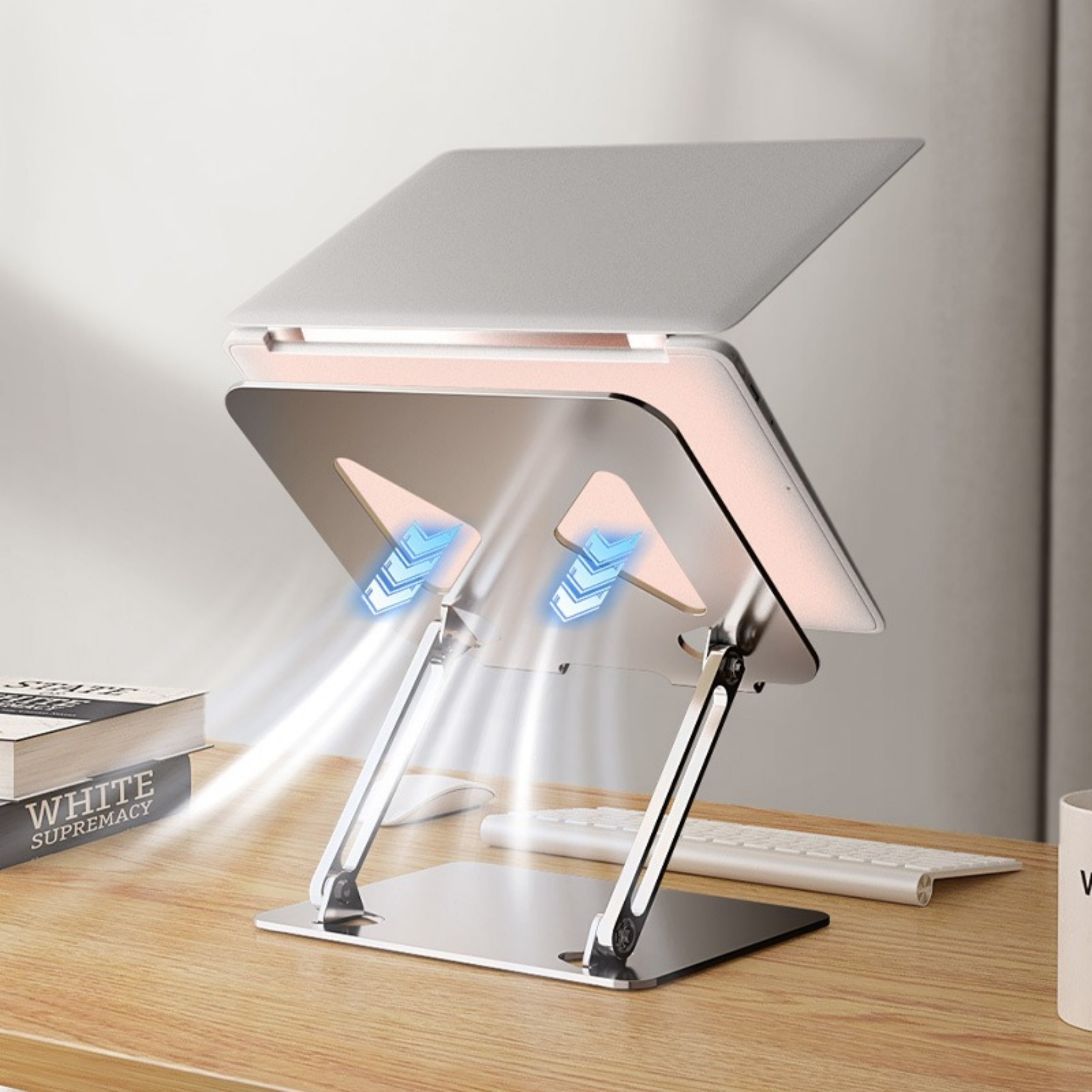 Laptop auf einem Aluminiumständer, mit Tastatur und Büchern auf einem Holztisch.