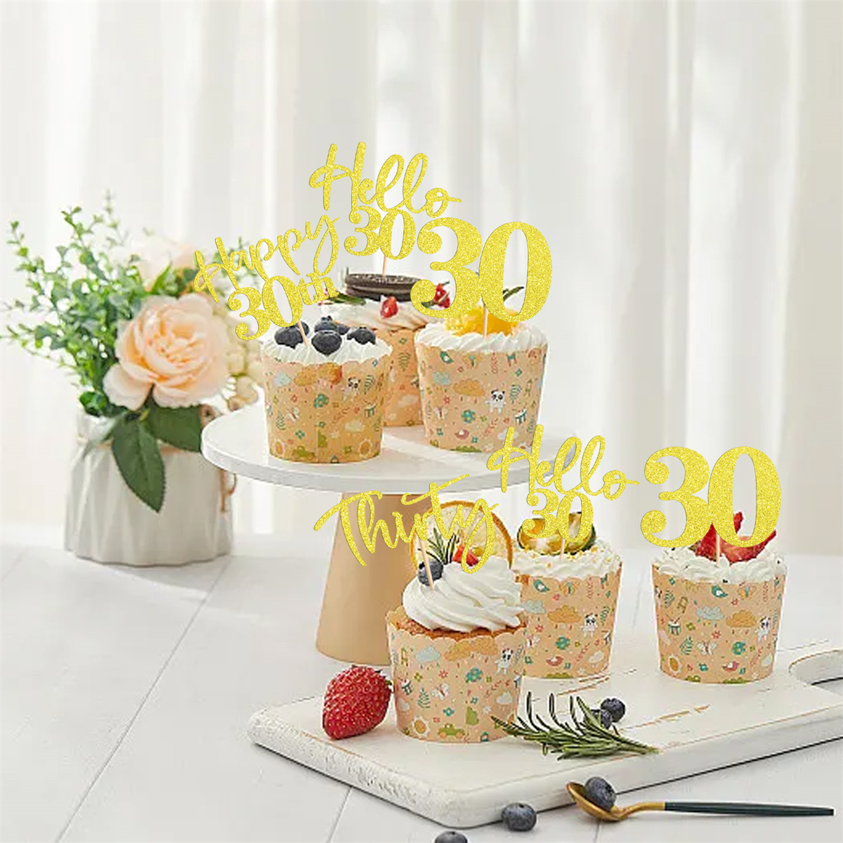 Cupcakes mit goldenen 'Hello 30'-Toppern, dekoriert mit Beeren, auf einem weißen Ständer.