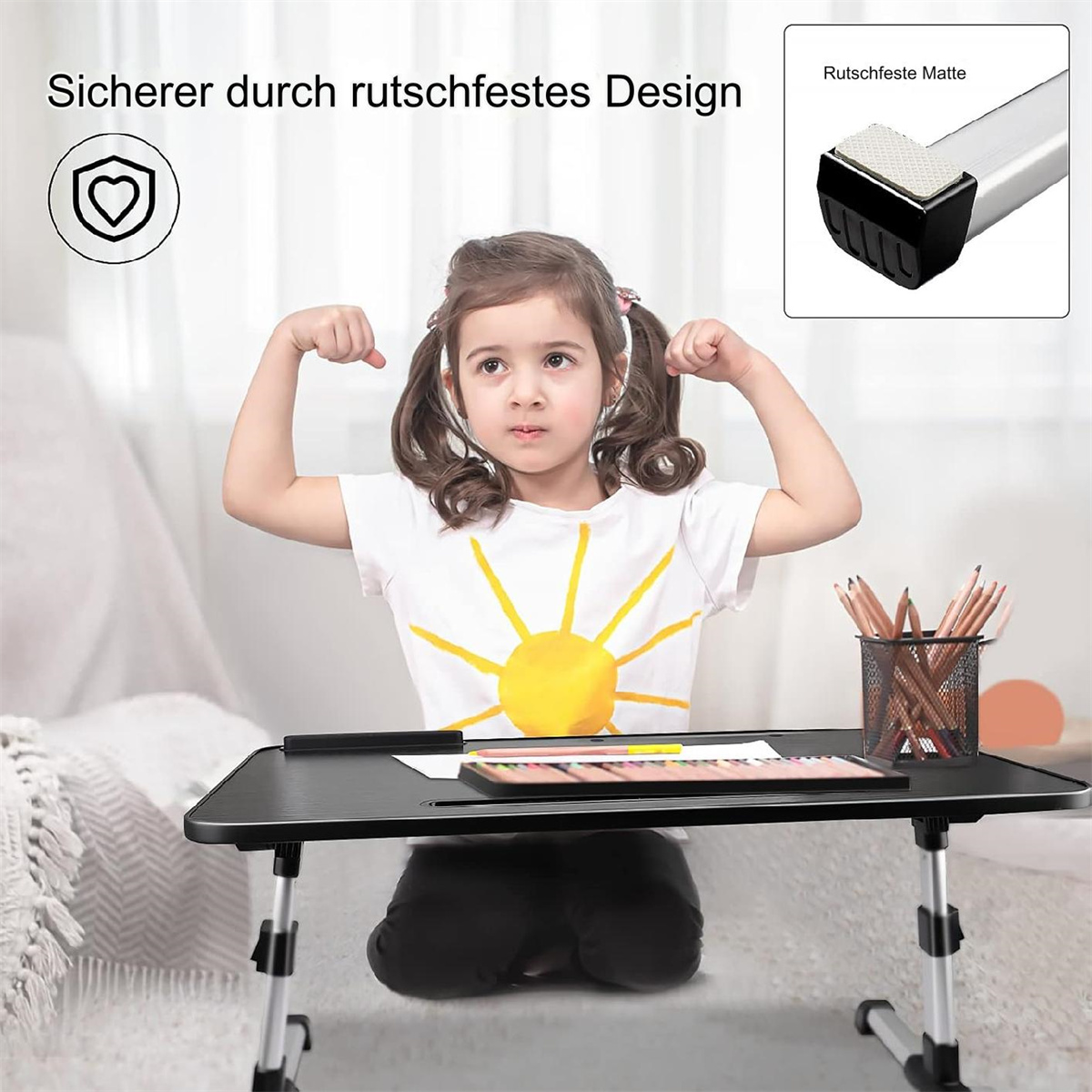 Ein junges Mädchen hebt die Arme in der Nähe eines schwarzen Tisches. Auf ihrem Shirt ist eine Sonne gezeichnet.