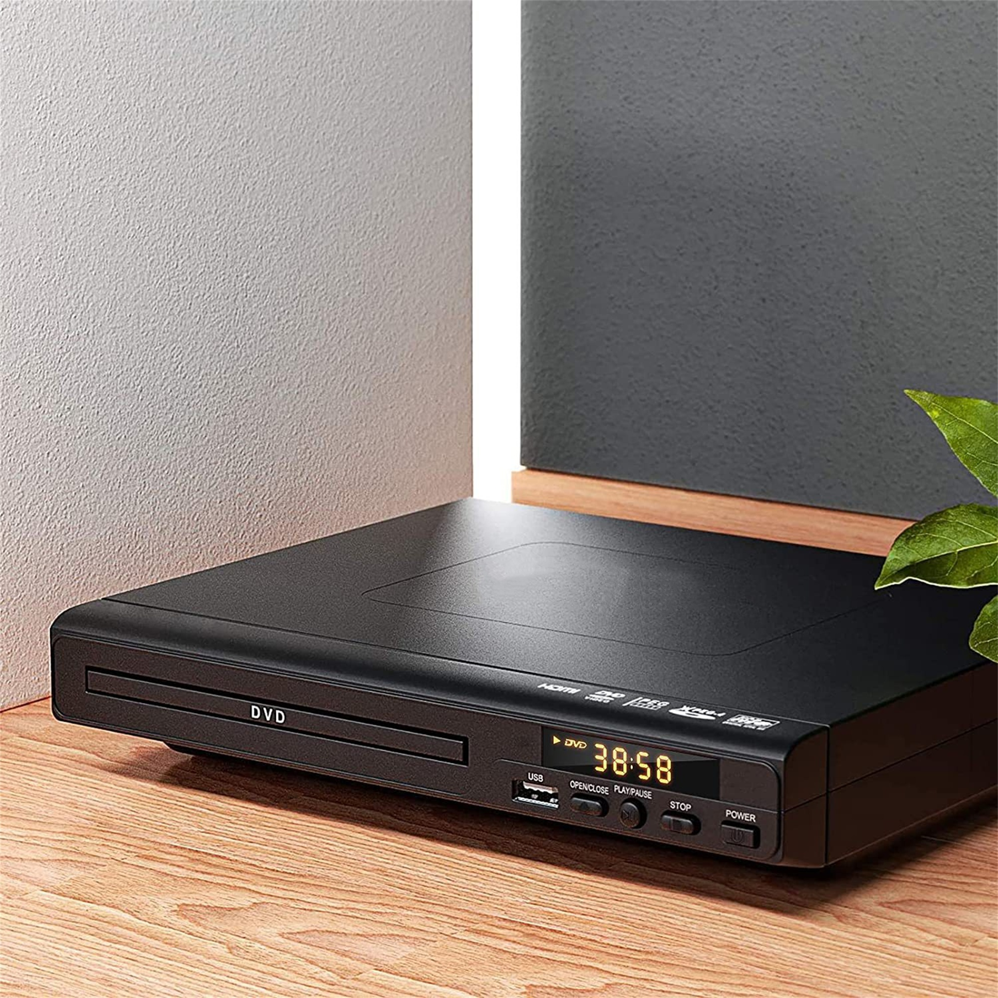 Ein schwarzer DVD-Player auf einem Holztisch neben einer Wand, die Anzeige zeigt die Zeit.