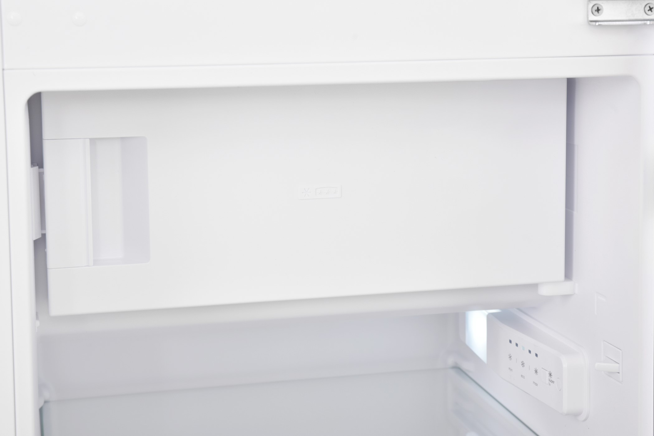 Inside a white refrigerator, a white drawer is open. The interior is white and brightly lit.