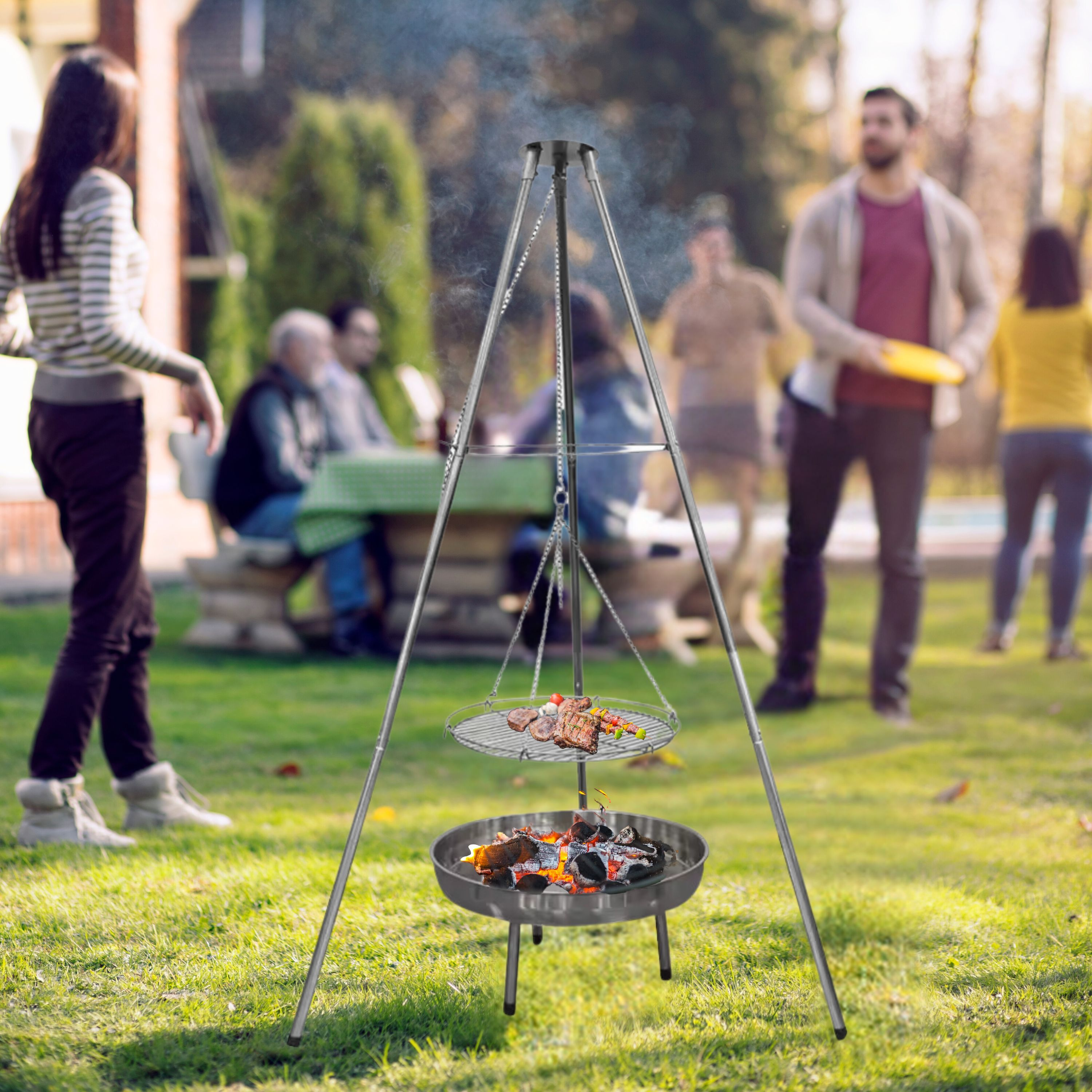 Grill mit Essen und Feuer. Menschen im Hintergrund, die die Natur genießen.