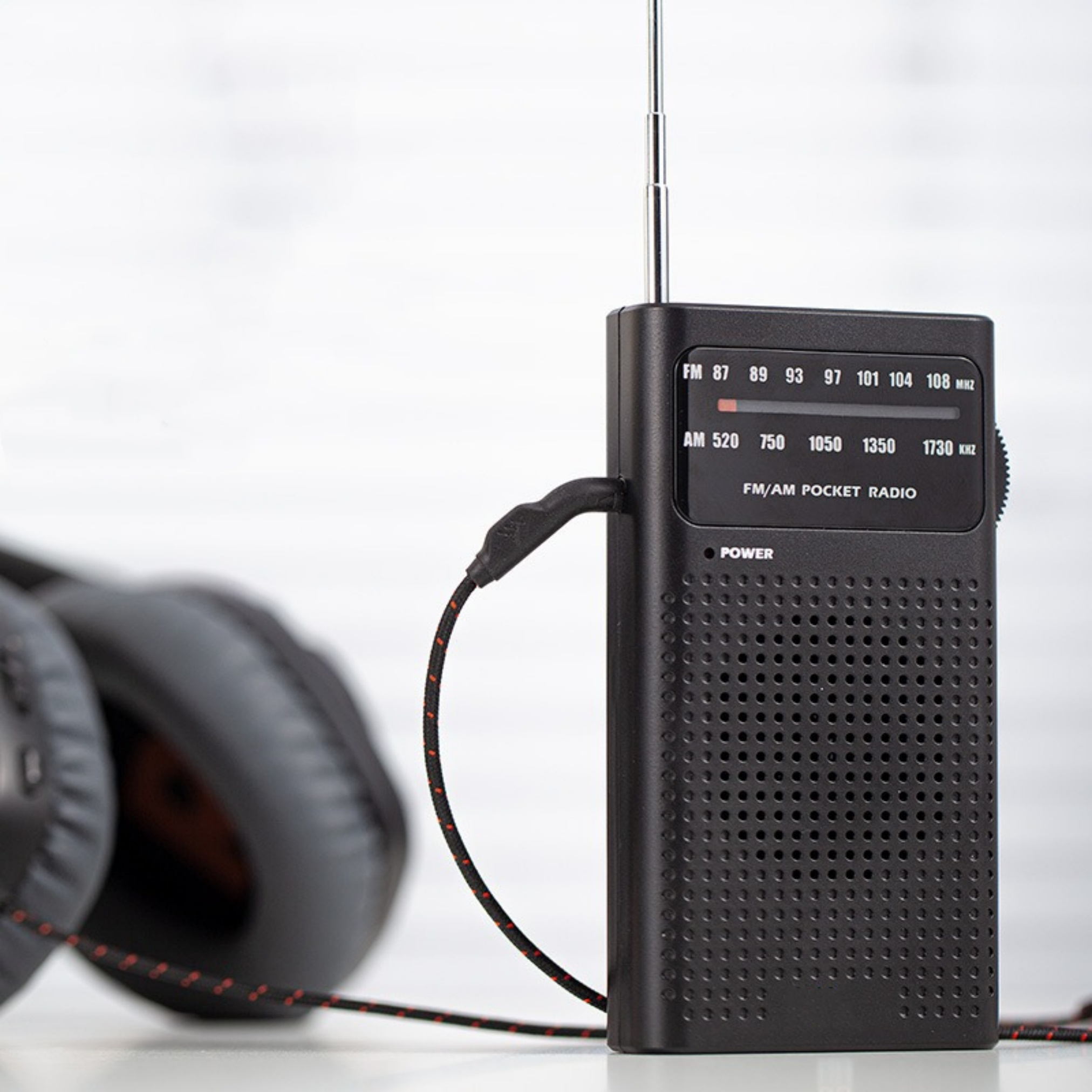 Ein schwarzes FM/AM-Taschenradio mit Kopfhörern, auf verschwommenem Hintergrund.