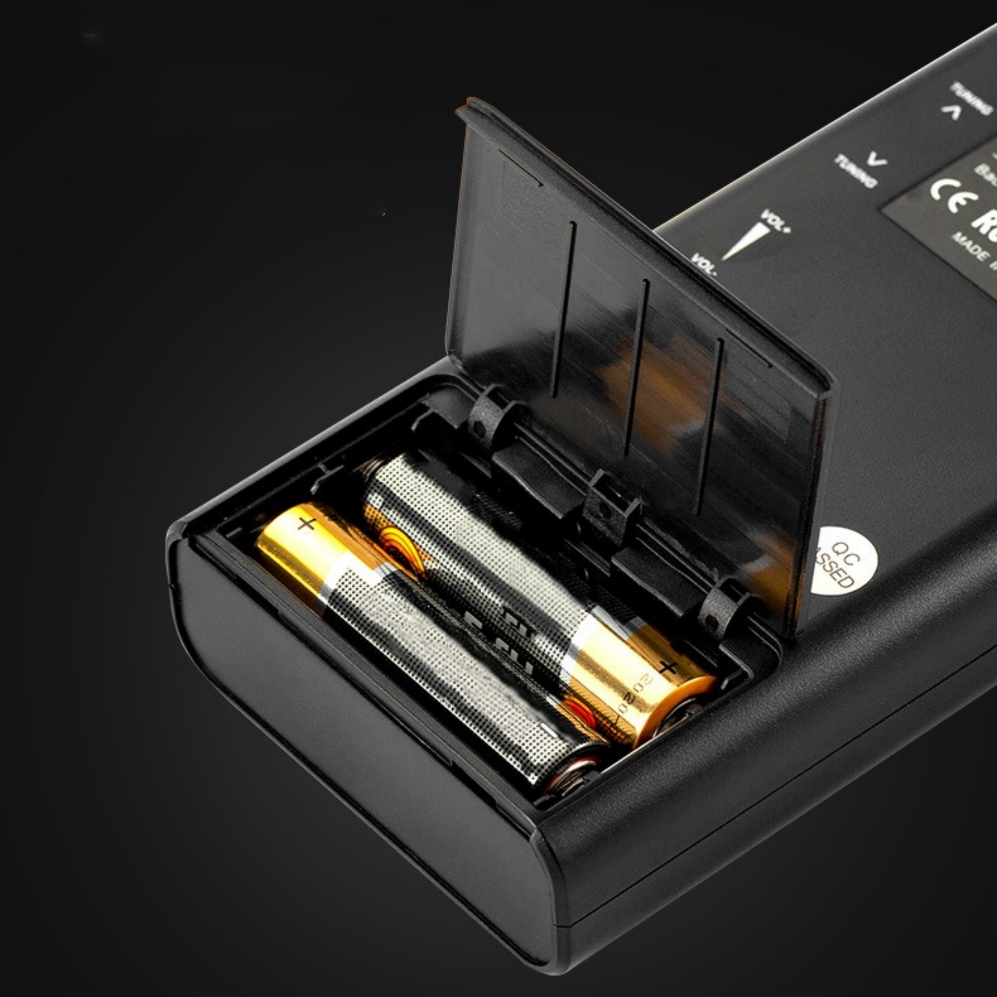 Nahaufnahme eines schwarzen Geräts mit offenem Batteriefach, das zwei AA-Batterien enthält.