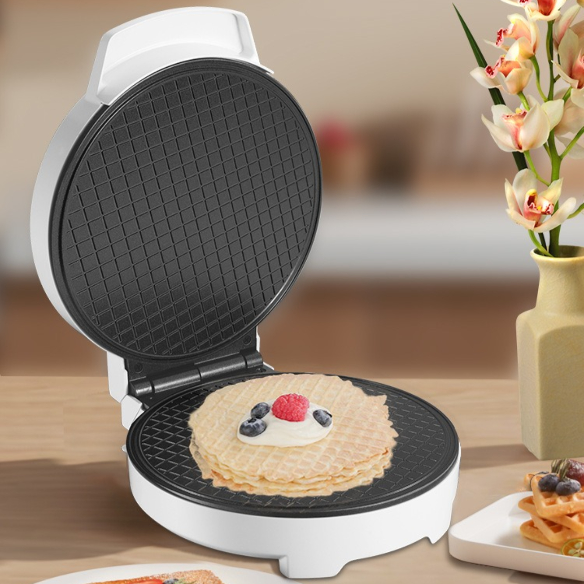 Waffeleisen mit Waffel, belegt mit Sahne und Beeren.