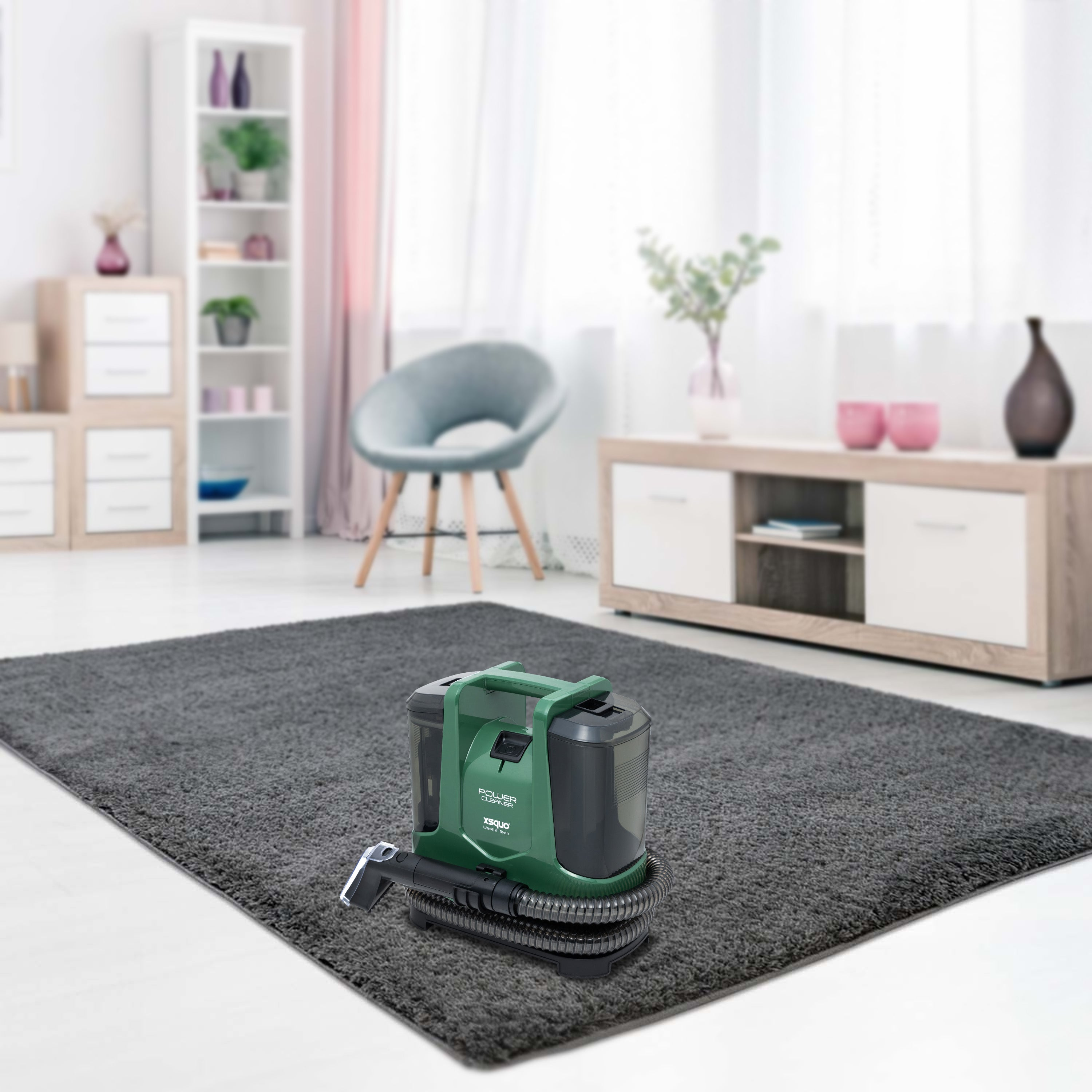 Una limpiadora de alfombras verde y negra sobre una alfombra gris. Un salón con muebles al fondo.