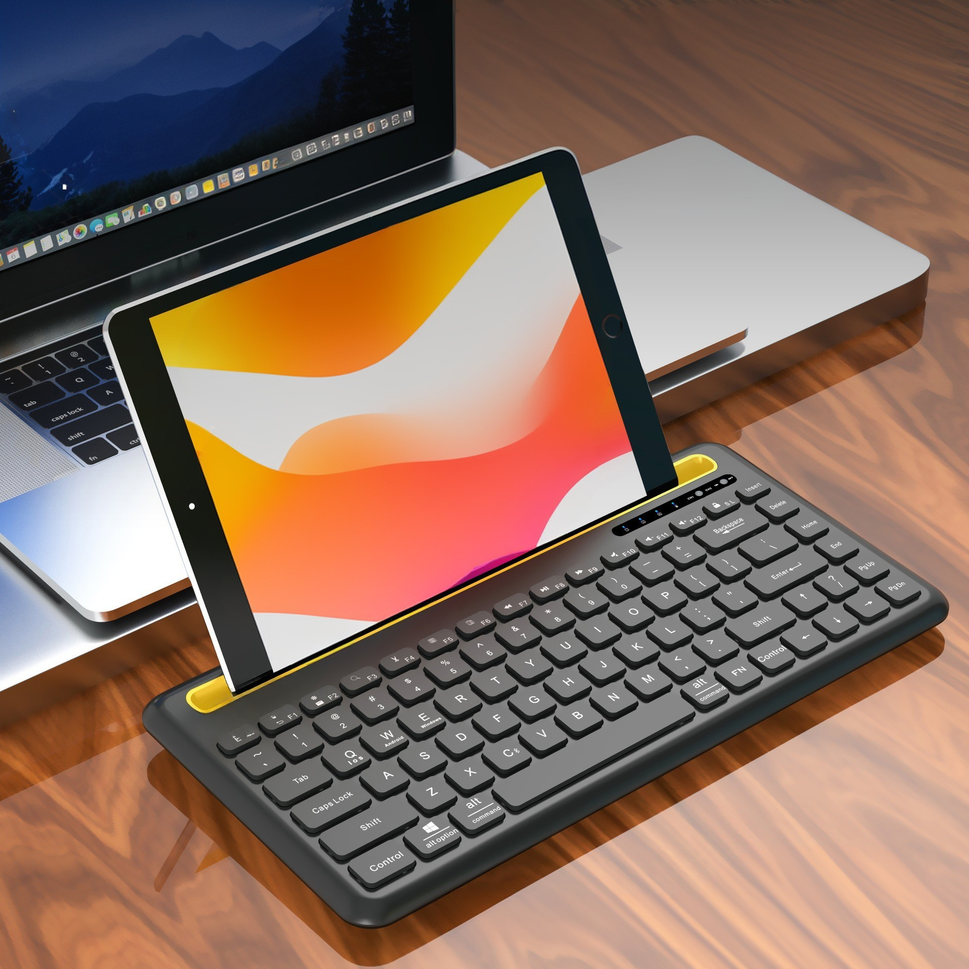 Tablet auf einer Tastatur. Die Tastatur ist schwarz mit gelben Akzenten. Laptop im Hintergrund.
