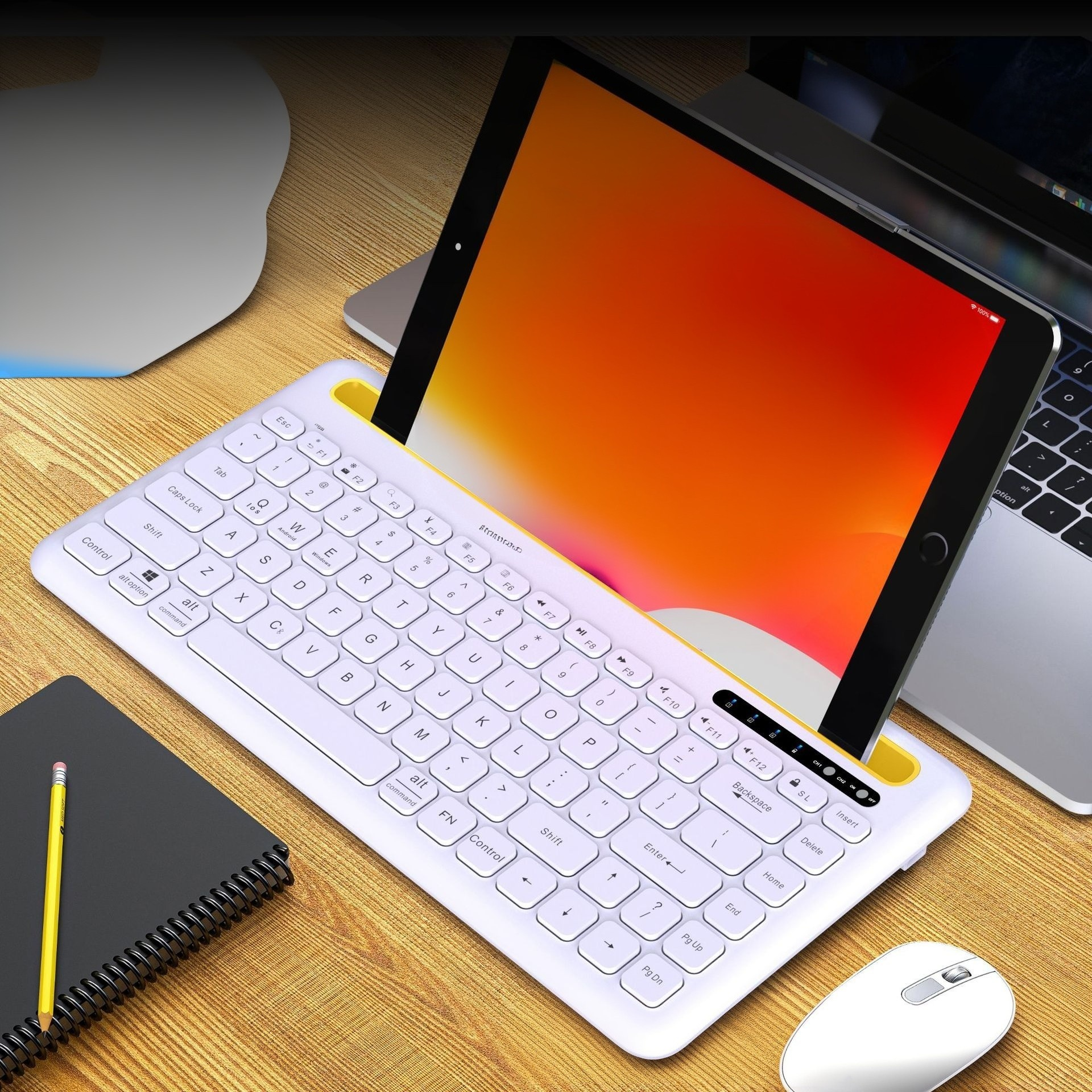 Tablet auf weißer Tastatur mit gelbem Rand. Maus und Notizbuch liegen ebenfalls auf Holz.